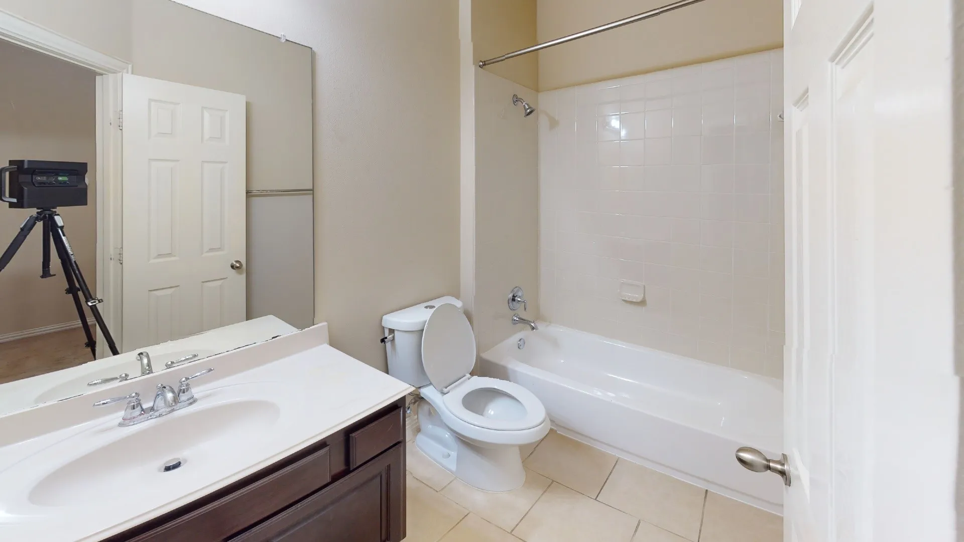 White tile flooring, single vanity with dark wood-finish cabinetry, integrated sink, and chrome fixtures