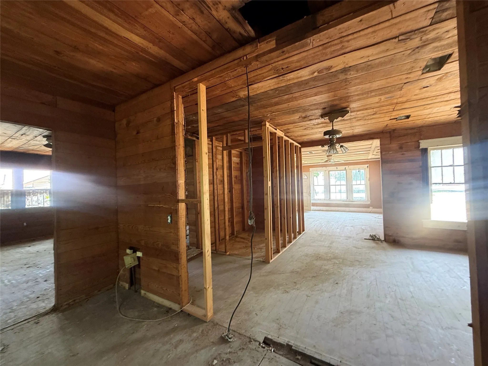 Interior framing, wood panel walls, wood plank ceilings, multiple windows, and exposed subflooring
