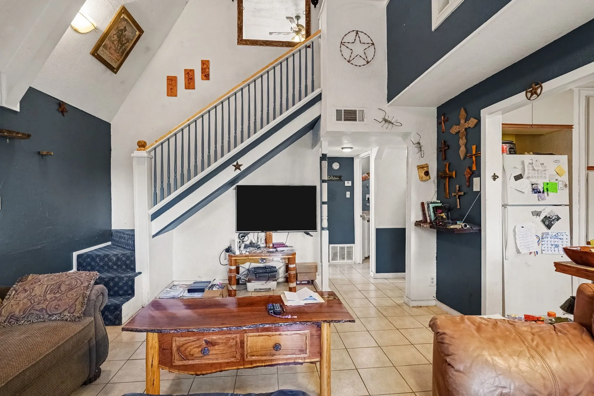 Living room view highlighting the open staircase leading to the upper loft area and feature wall details.