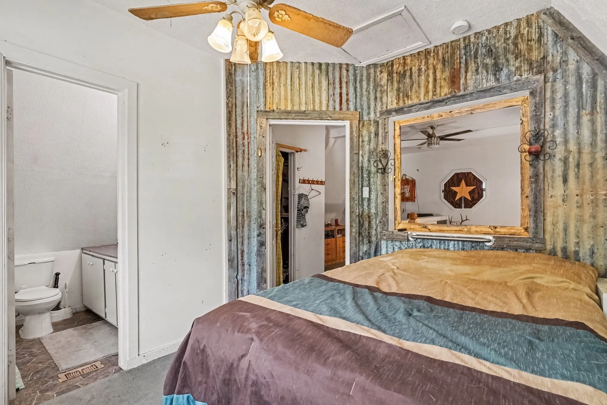 Upper-level bedroom featuring sloped architectural ceilings, decorative accent wall, and ceiling fan.