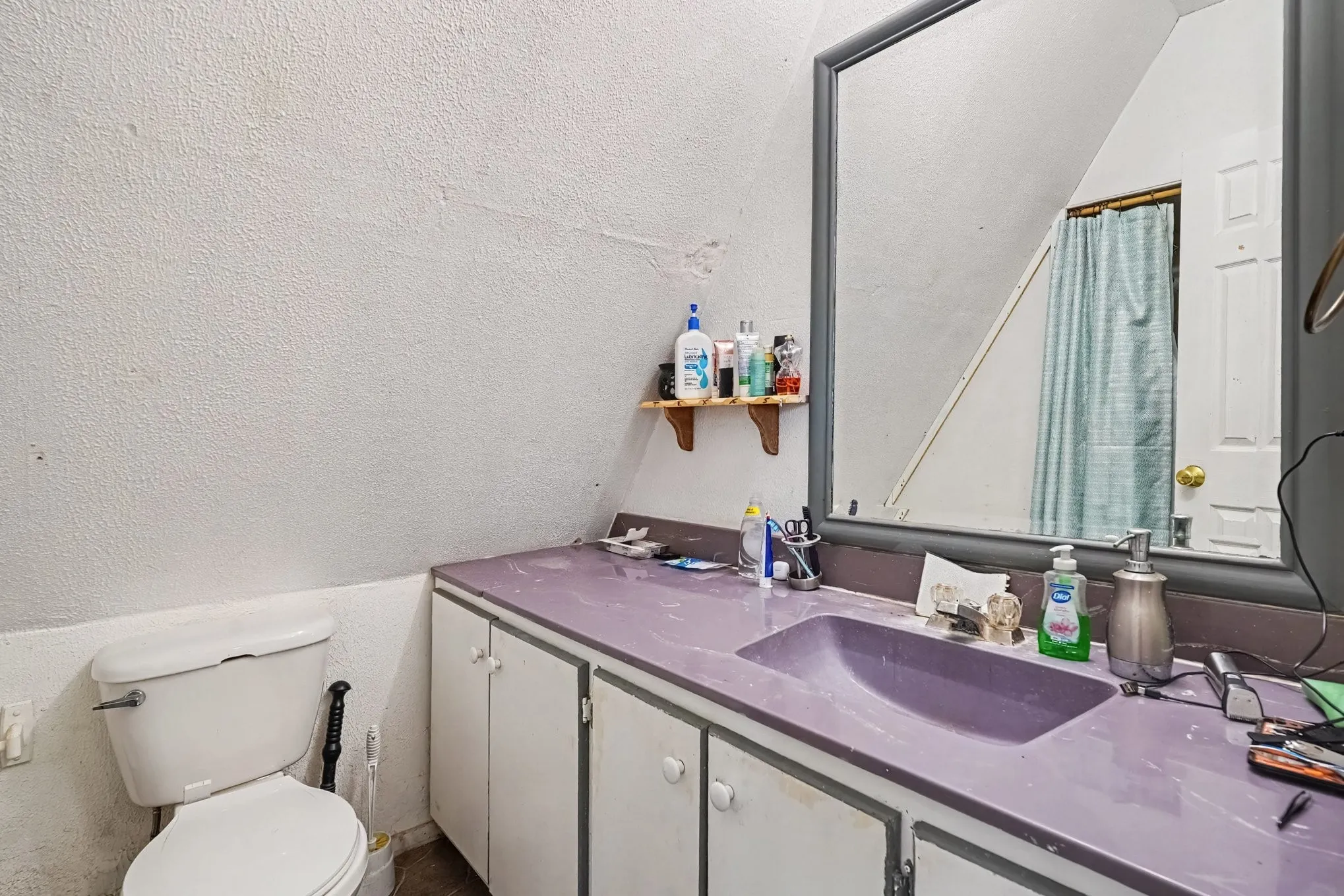 Upper-level full bathroom featuring a long double-sink vanity with expansive mirror under the sloped ceiling.
