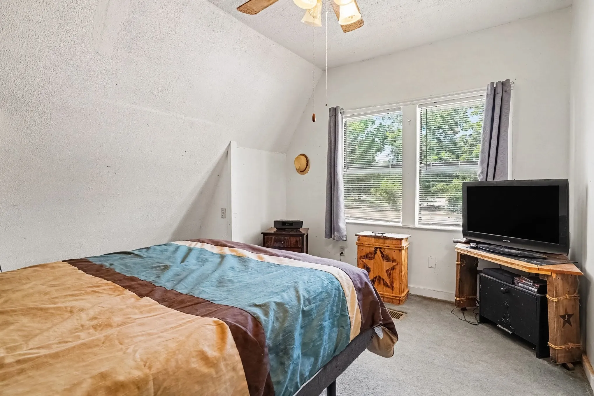 Comfortable bedroom setup with window lighting, neutral walls, and space for bedroom furniture.