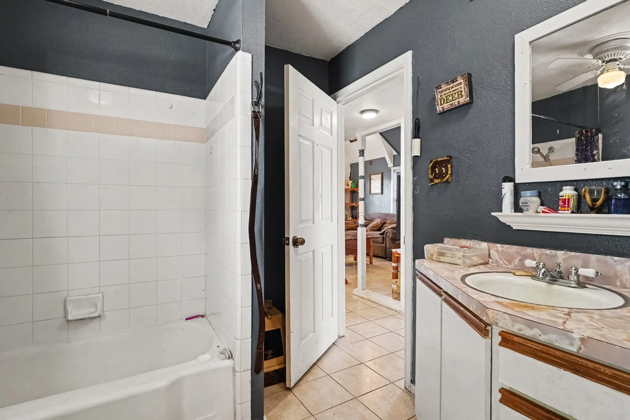 Main-floor bathroom with dark accent walls, updated vanity with gold hardware, and walk-in shower surround.
