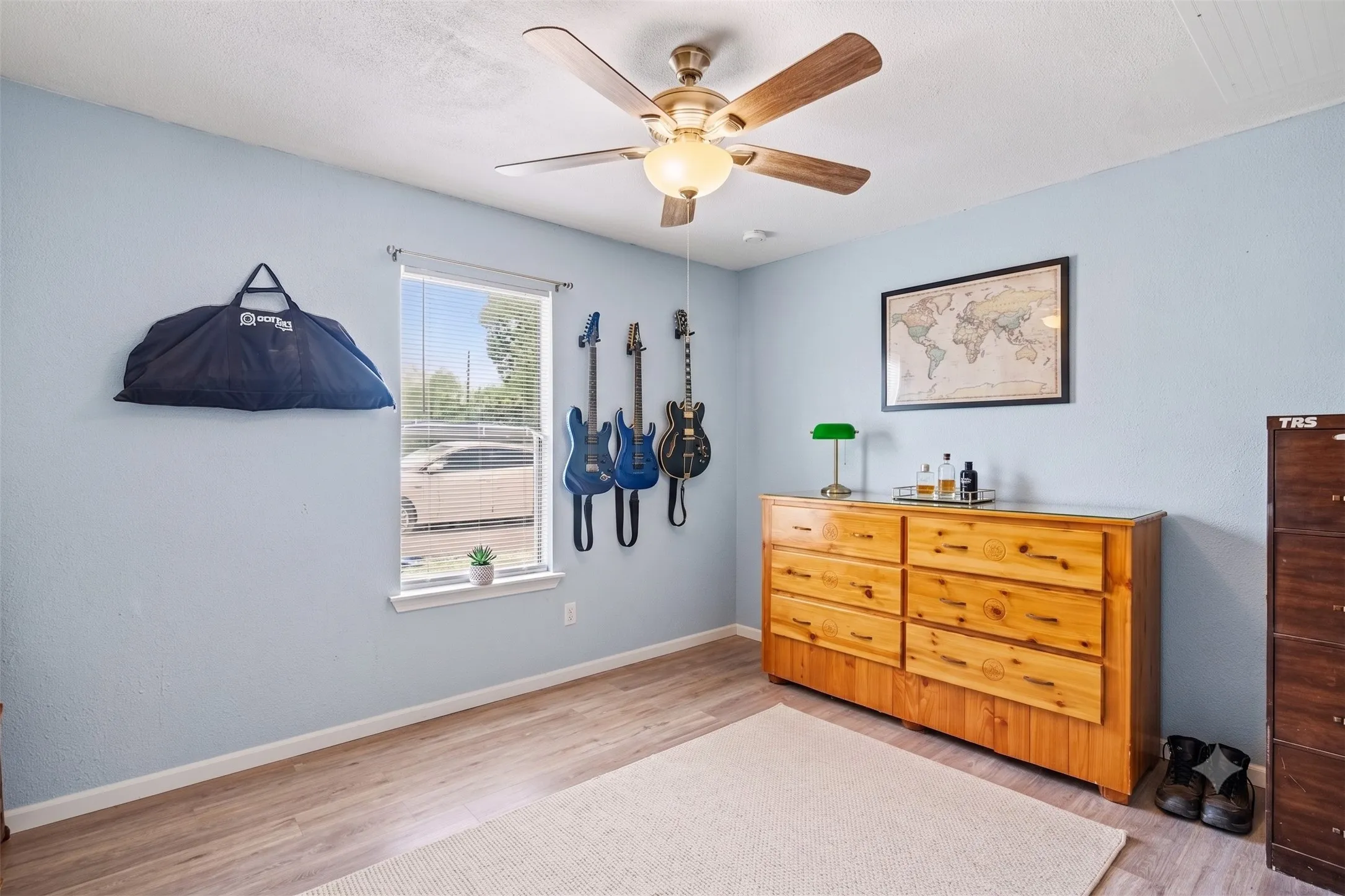 Secondary bedroom featuring soft blue wall paint, central ceiling fan, and wood-look flooring.