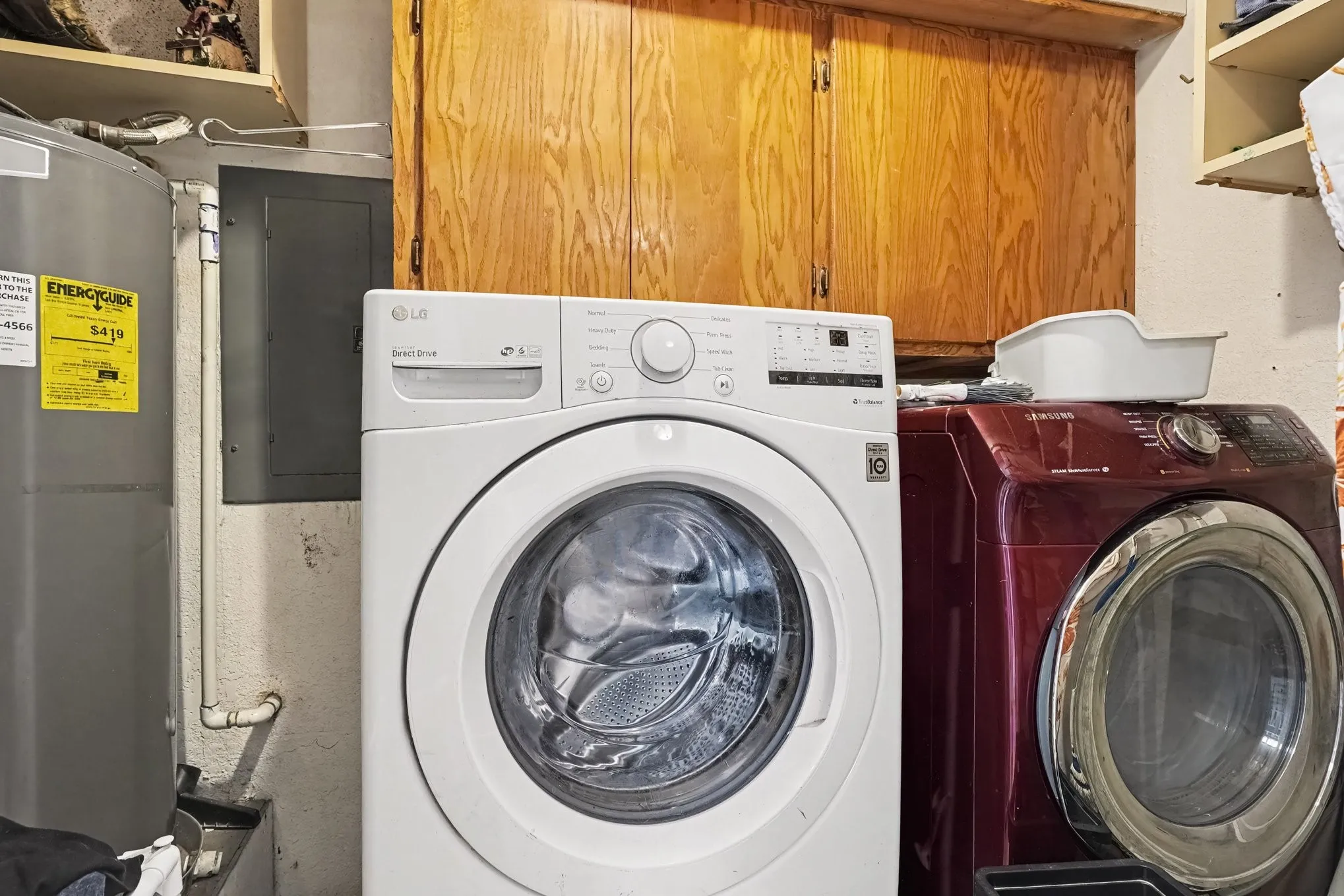 Dedicated laundry room fitted with front-loading washer and dryer set below upper wood cabinets.