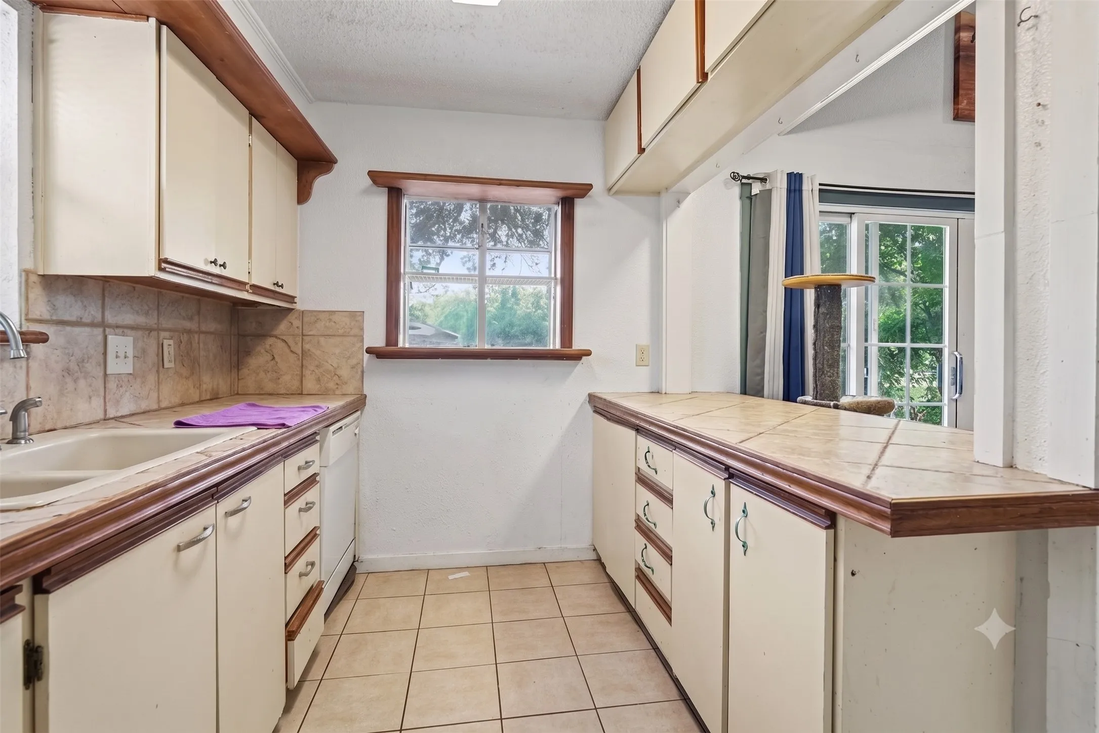 Galley kitchen layout displaying generous counter workspace, wood-trimmed cabinetry, and rear window lighting.