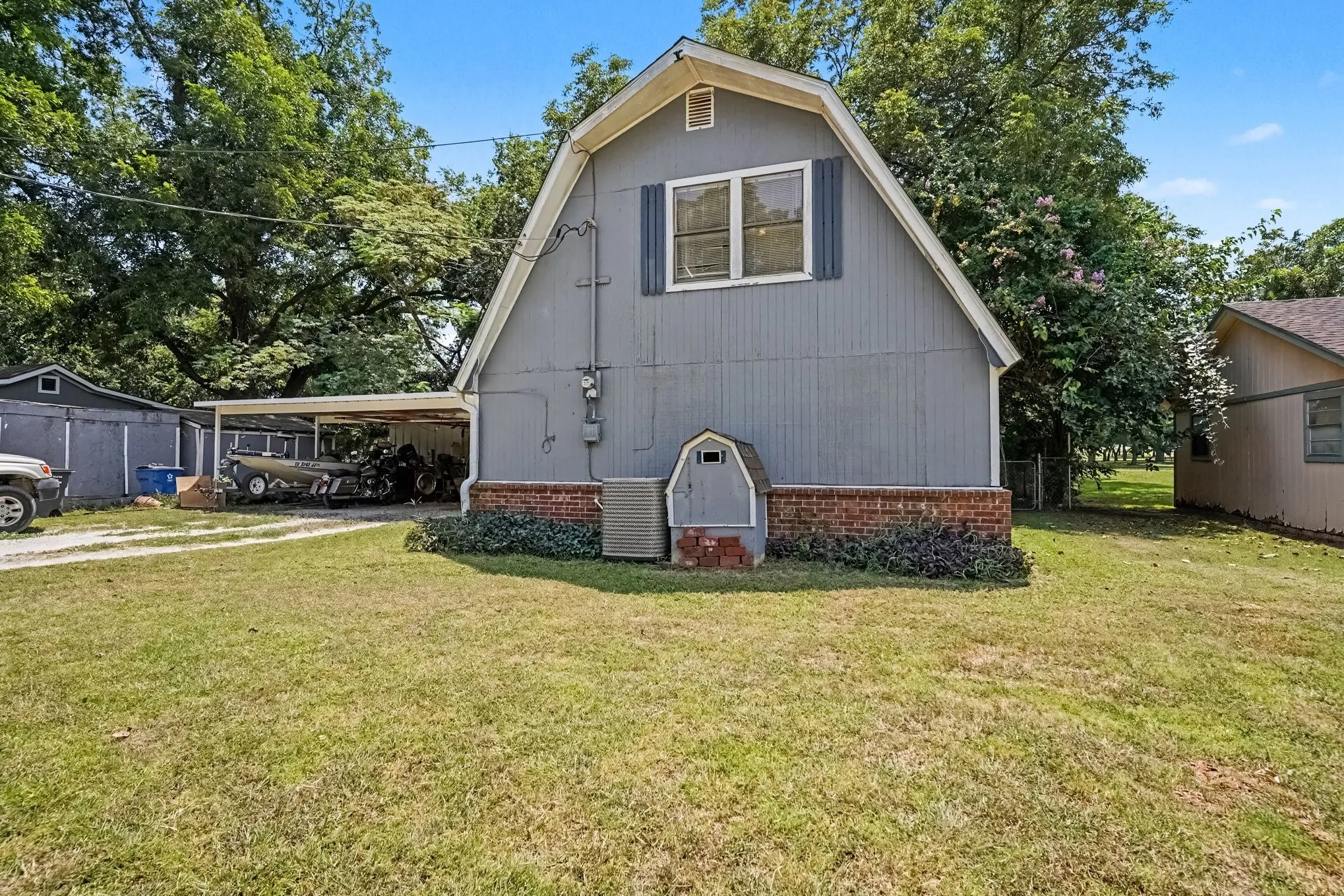 Straight-on front view showcasing the gambrel architectural style, brick lower accent facade, and front yard.