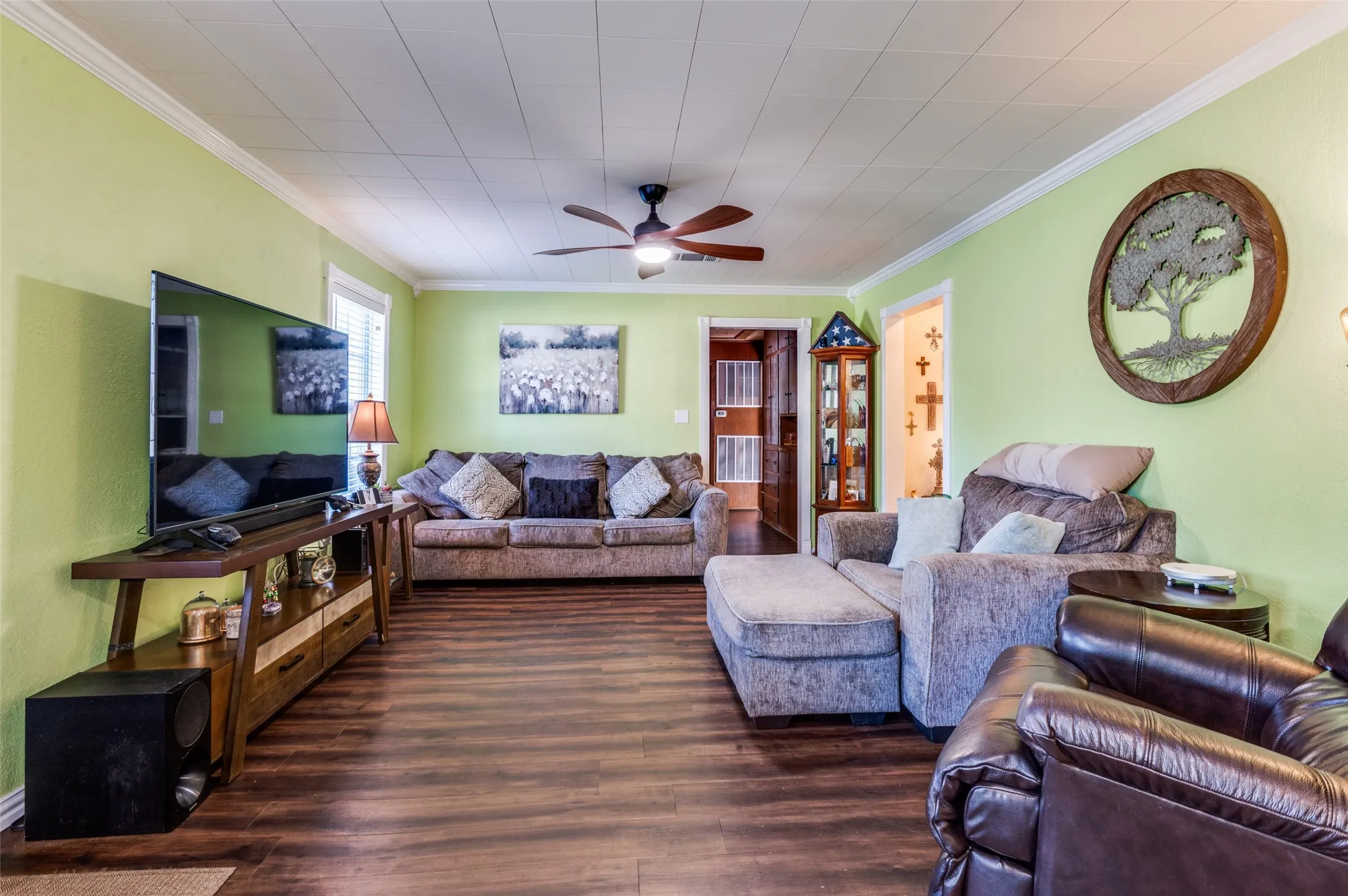Wood-finish flooring throughout, ceiling fan with integrated lighting, and a white paneled ceiling