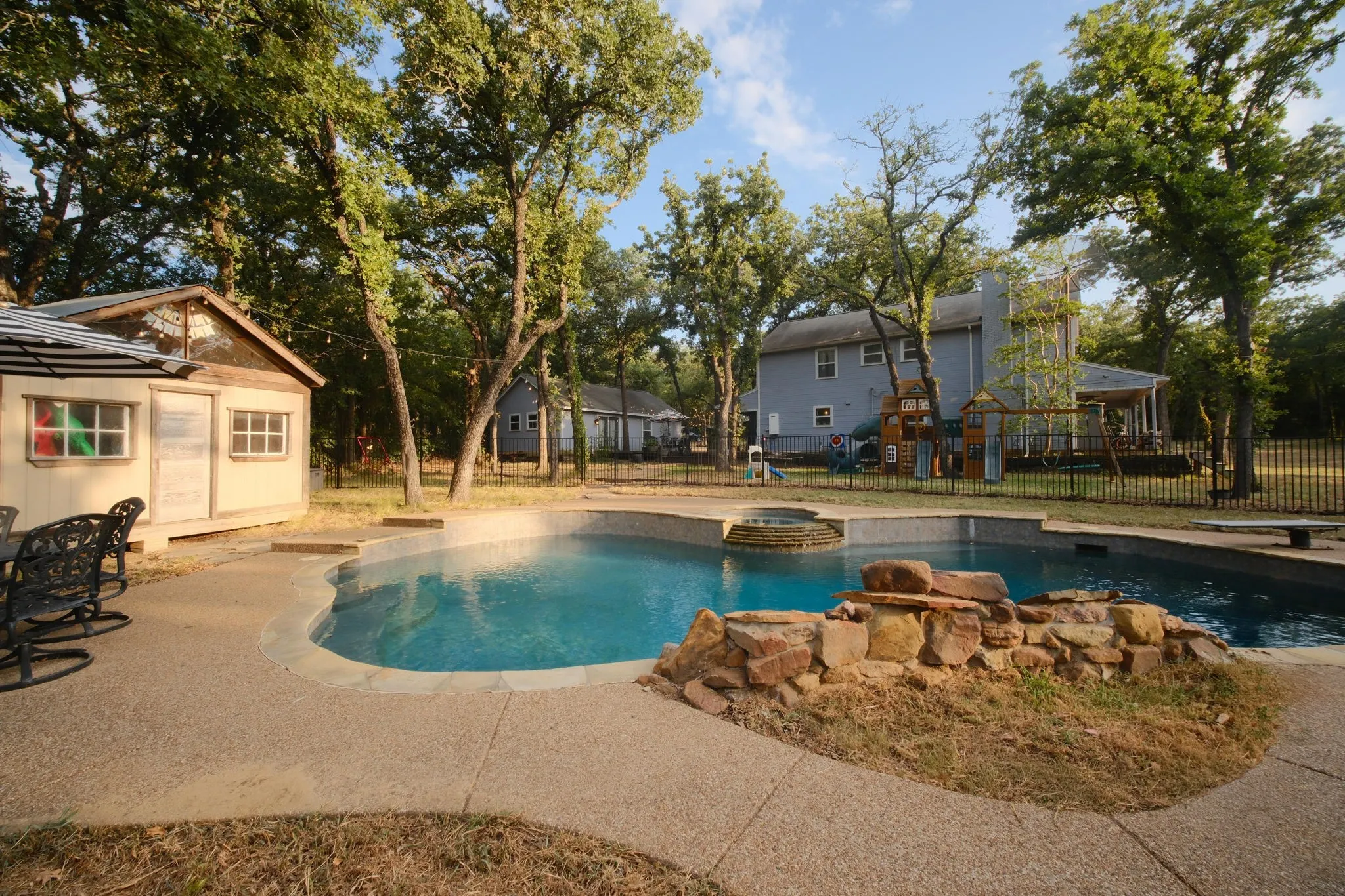 Freeform swimming pool with integrated spa and rock water feature