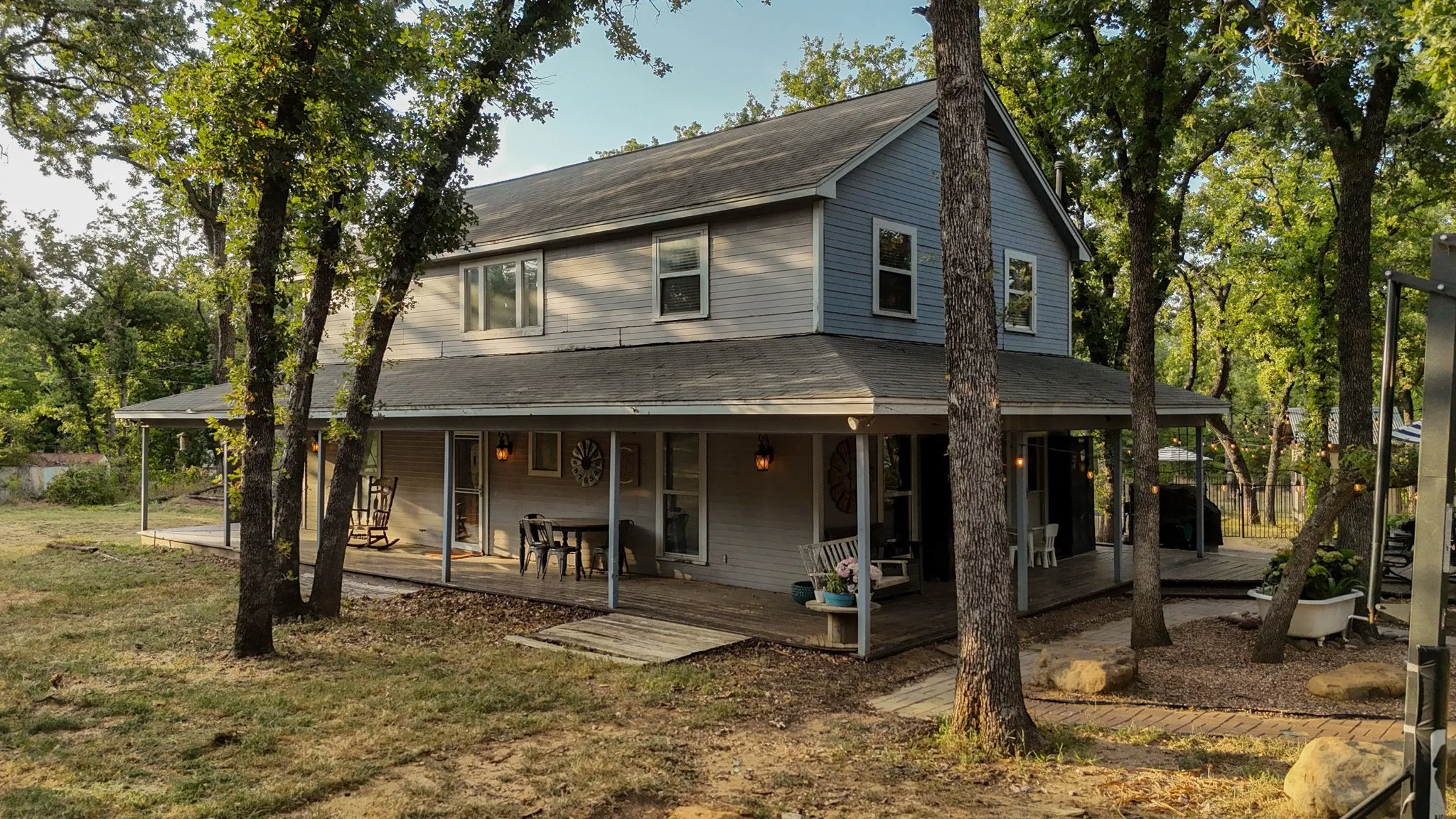 Two-story residence featuring light blue horizontal siding, a covered porch wrapping around the front and side, and multiple windows