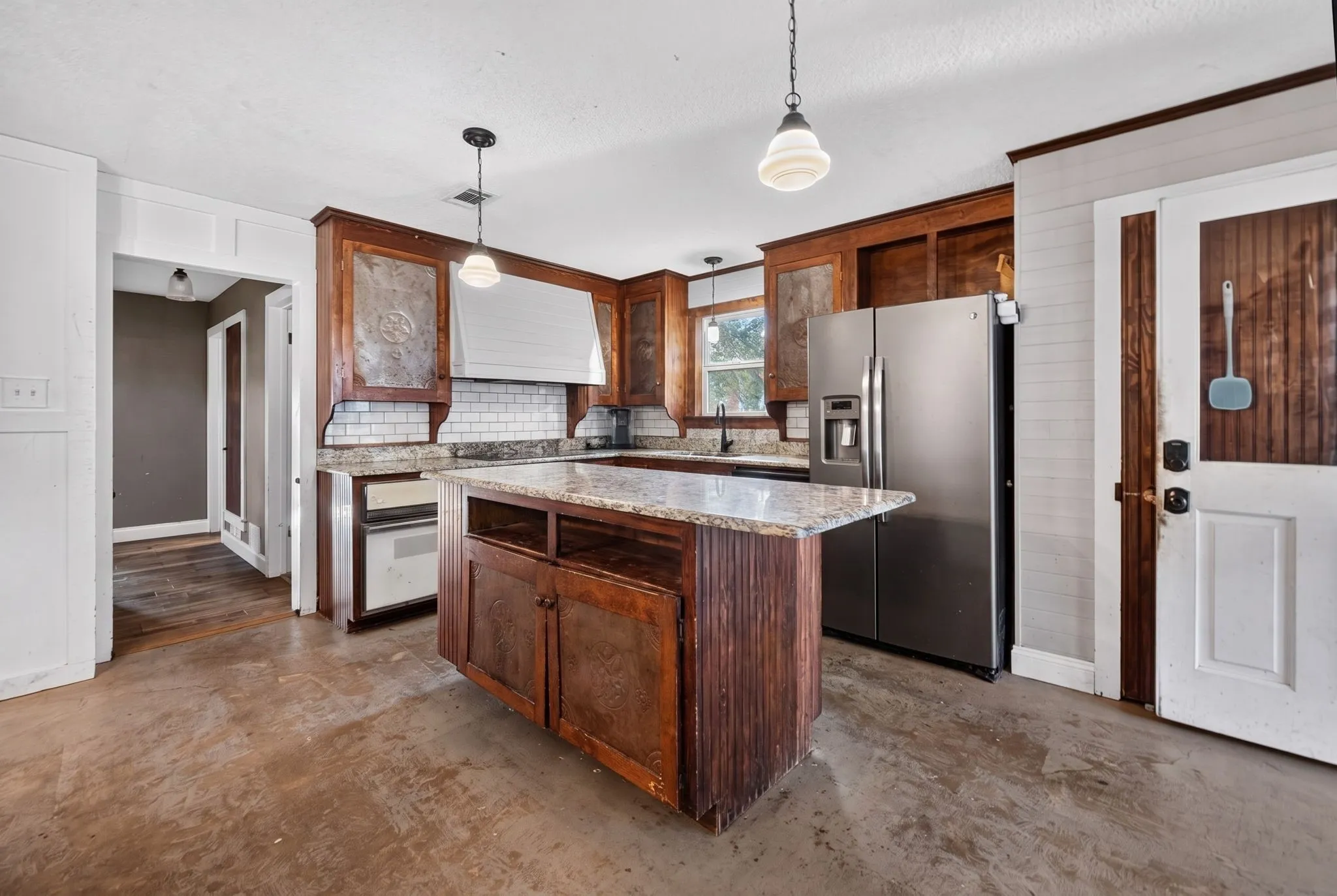 Kitchen featuring stainless steel appliances, wood cabinetry, granite countertops, and subway tile backsplash