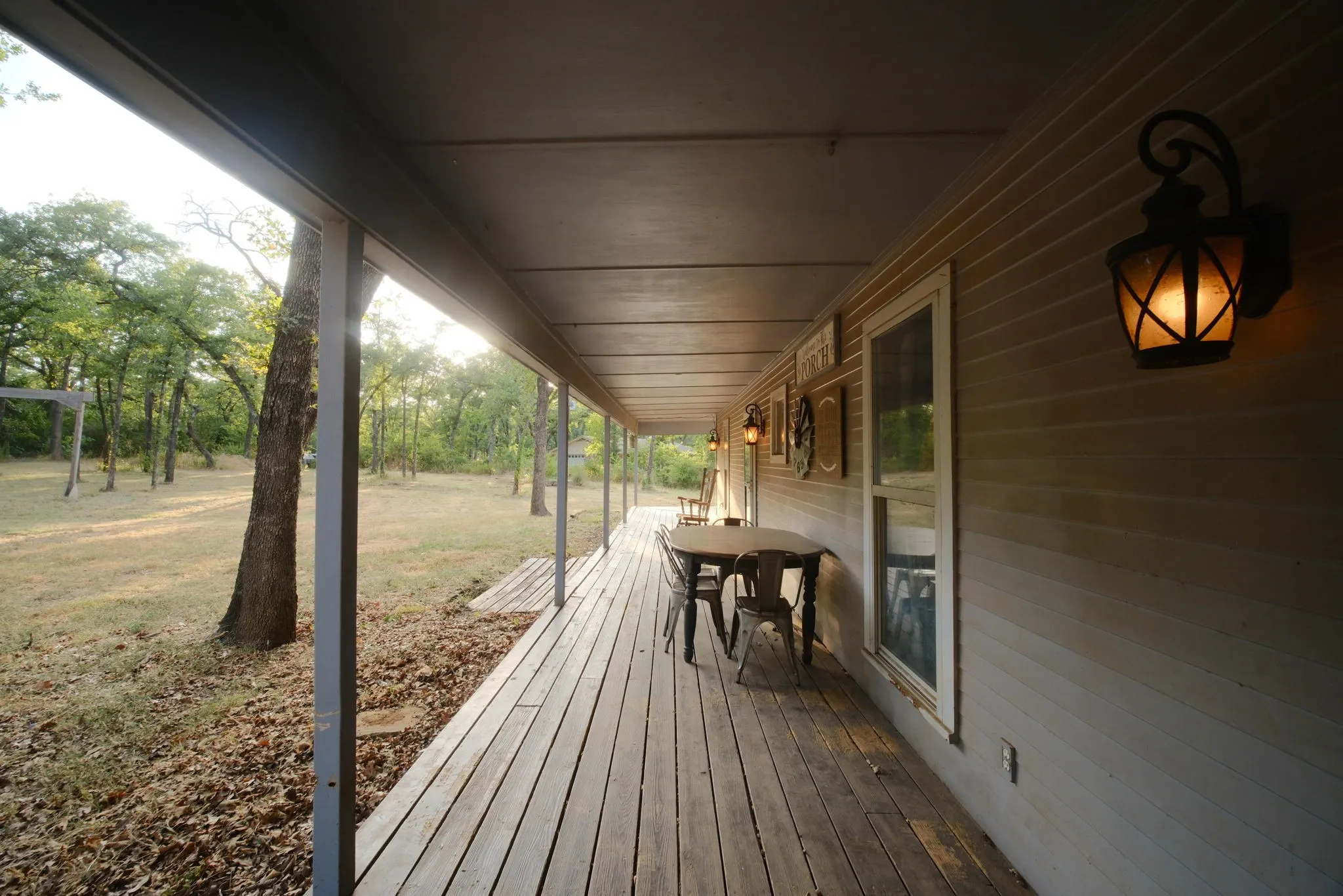 Expansive covered porch featuring wood-finish decking, support columns, and pendant​​‌​​​​‌​​‌‌​‌‌​​​‌‌​‌​‌​‌​​​‌​​ lighting