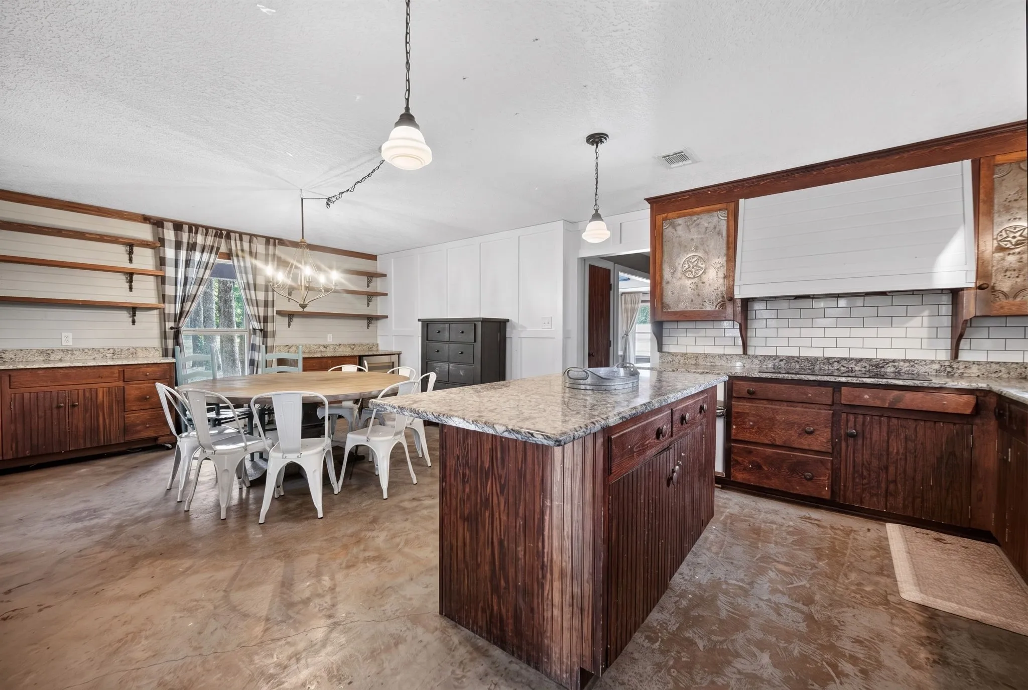 Kitchen featuring wood-finish cabinetry, granite countertops, subway tile backsplash, a kitchen island, and polished concrete flooring