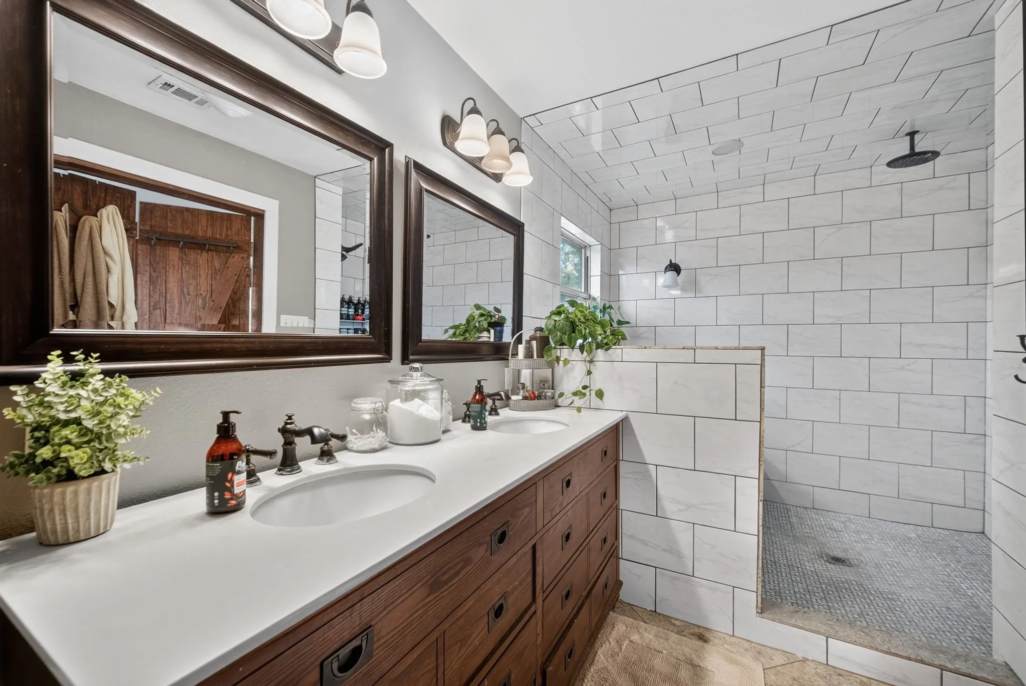 Double vanity with integrated sinks, dark wood-finish cabinetry, and framed mirrors
