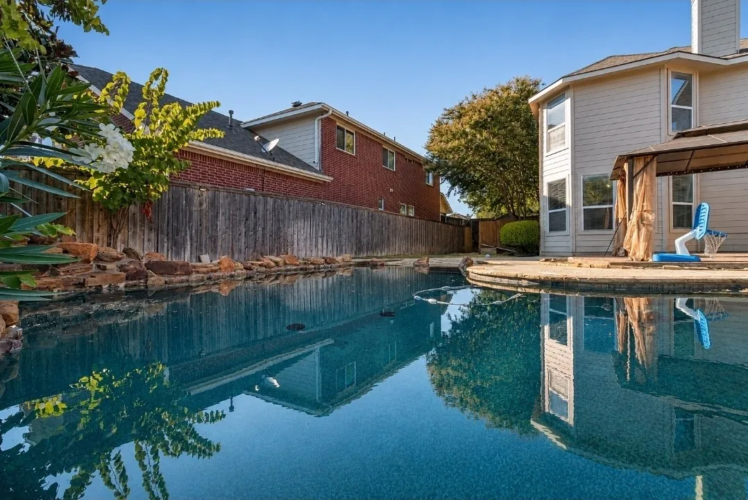 In-ground swimming pool with a rock border and an adjacent patio area