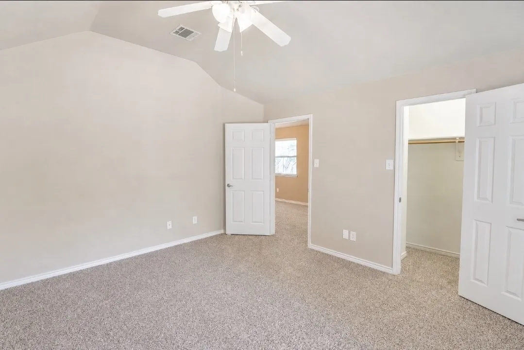 Carpeted room featuring a vaulted ceiling and a ceiling fan