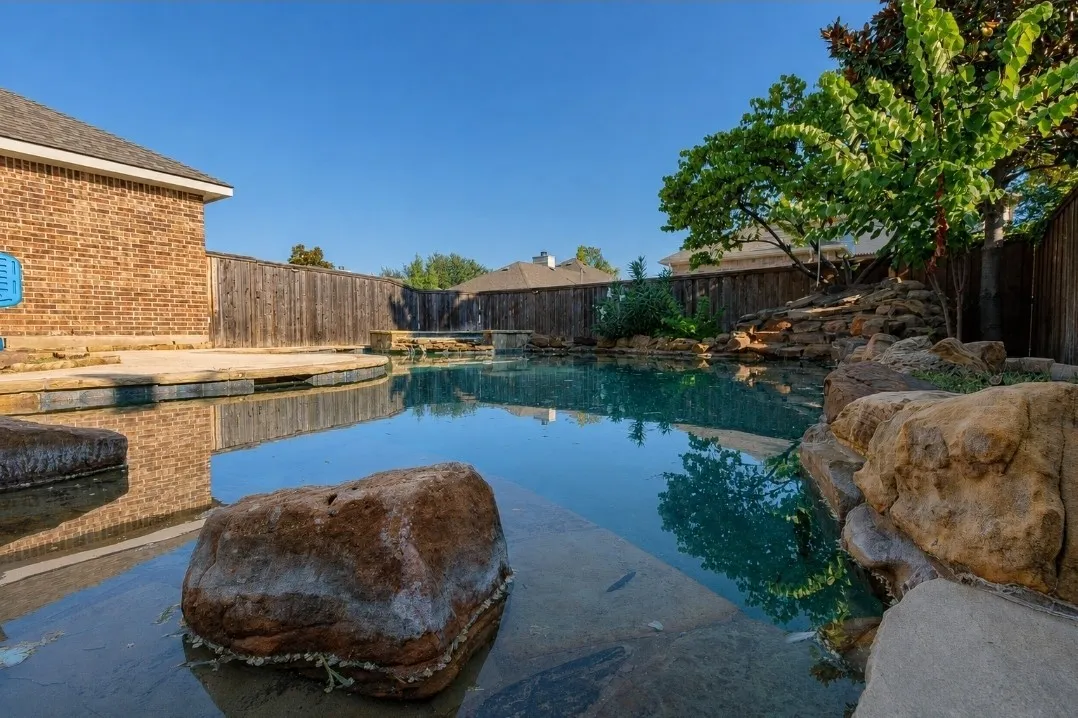 Swimming pool featuring natural stone elements, integrated spa, and surrounding hardscaping