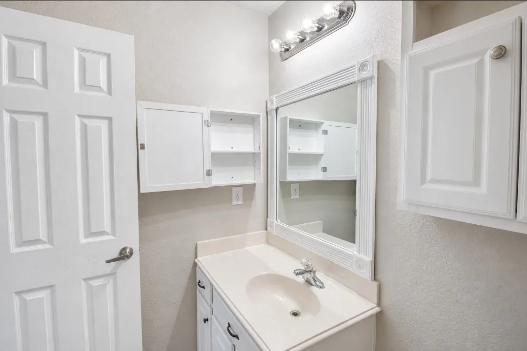 Vanity with integrated sink, framed mirror, and wall-mounted lighting