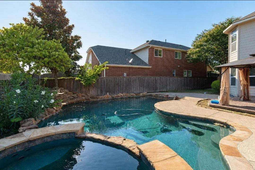 Curved swimming pool with integrated spa and rock waterfall feature