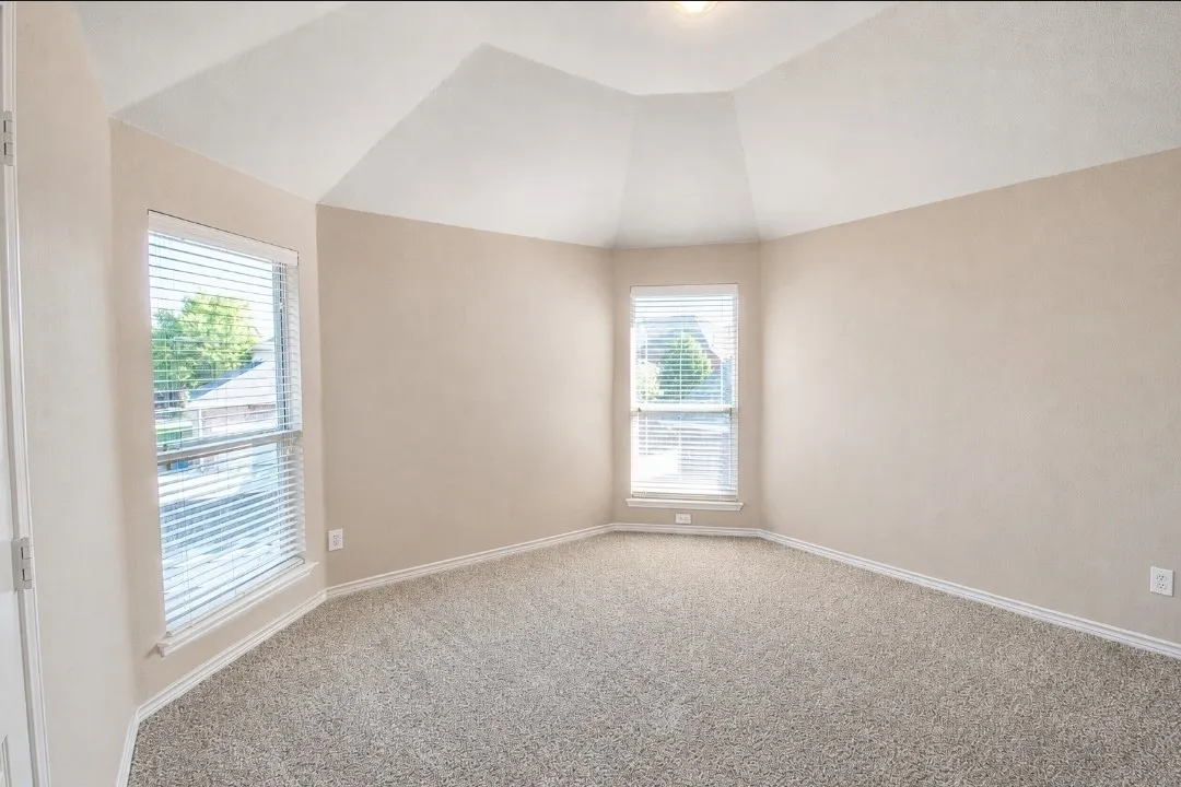 Textured carpeting, neutral wall paint, and a vaulted ceiling