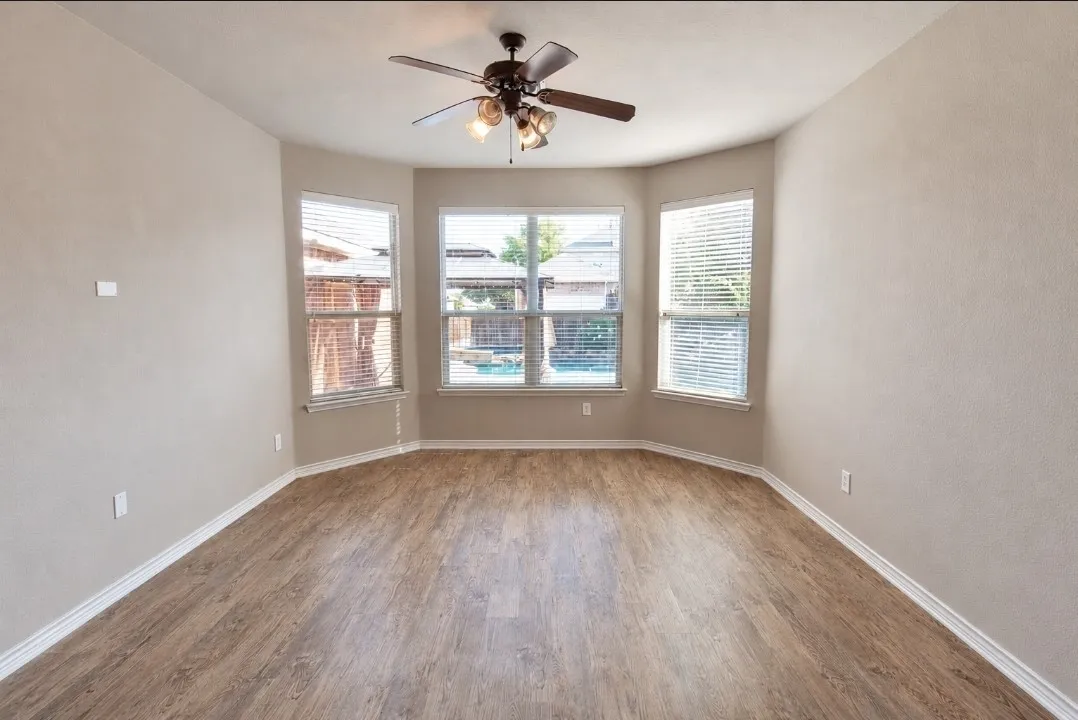 Bay window with multiple windows, wood-finish flooring, ceiling fan, and painted walls
