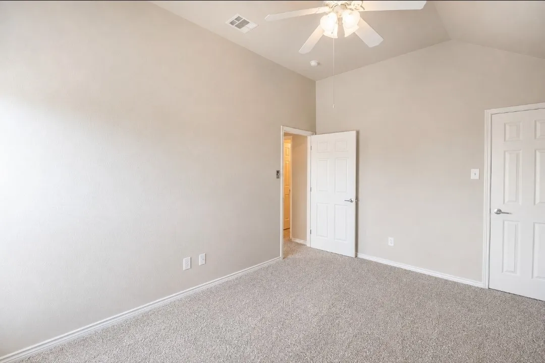 Vaulted ceiling with a ceiling fan, light gray carpeting, and white paneled doors
