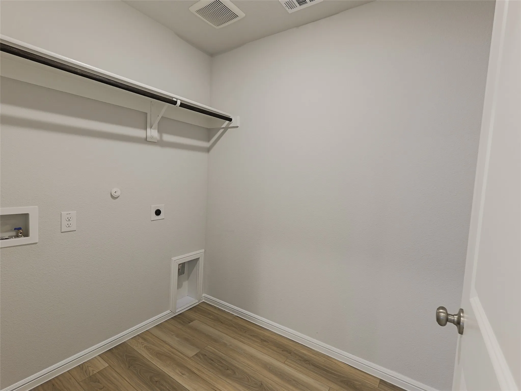 Utility room featuring wood-finish flooring, white painted walls, recessed ceiling lighting, and wall-mounted storage fixtures