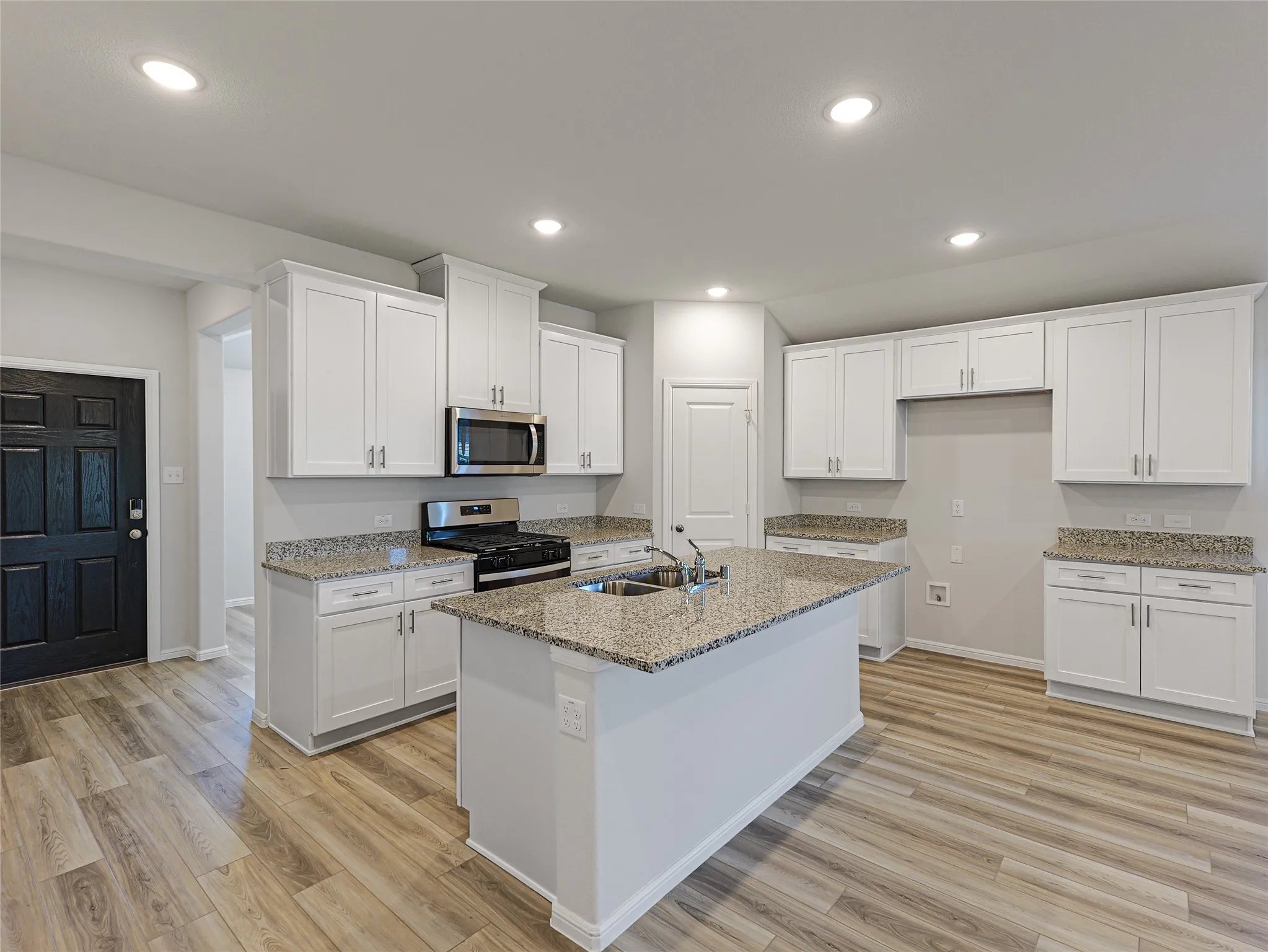 Open-concept kitchen featuring an island, recessed lighting, wood-finish flooring, white cabinetry, and stainless steel appliances