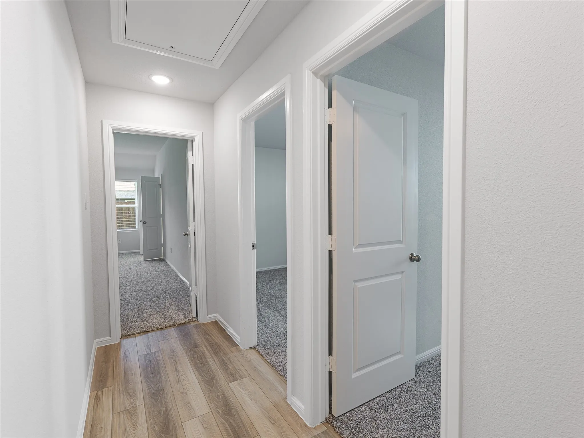 Hallway with wood-finish flooring, recessed lighting, and white panel doors