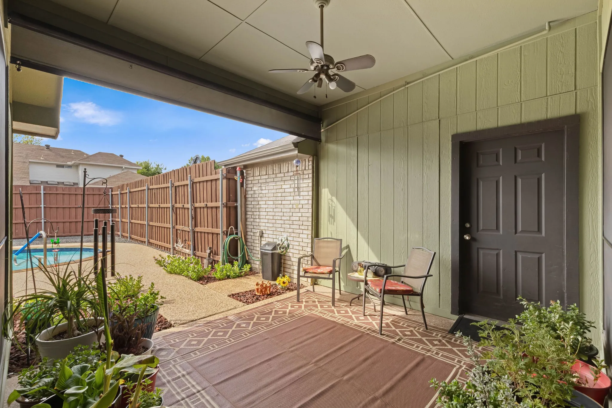 Covered patio with a ceiling fan, board-and-batten siding, and an exterior door