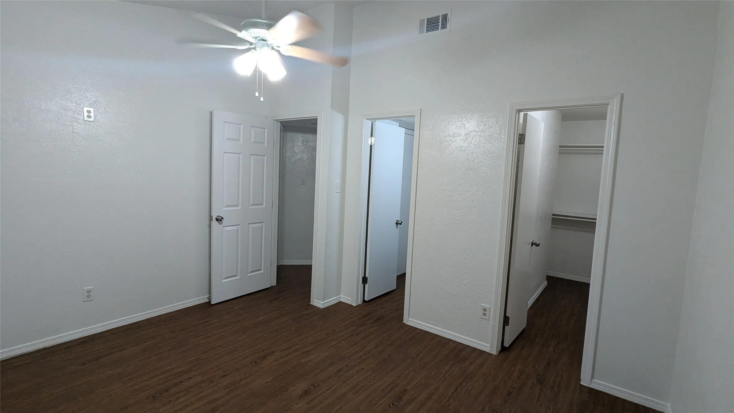 Wood-finish flooring, white walls, and a ceiling fan with integrated lighting