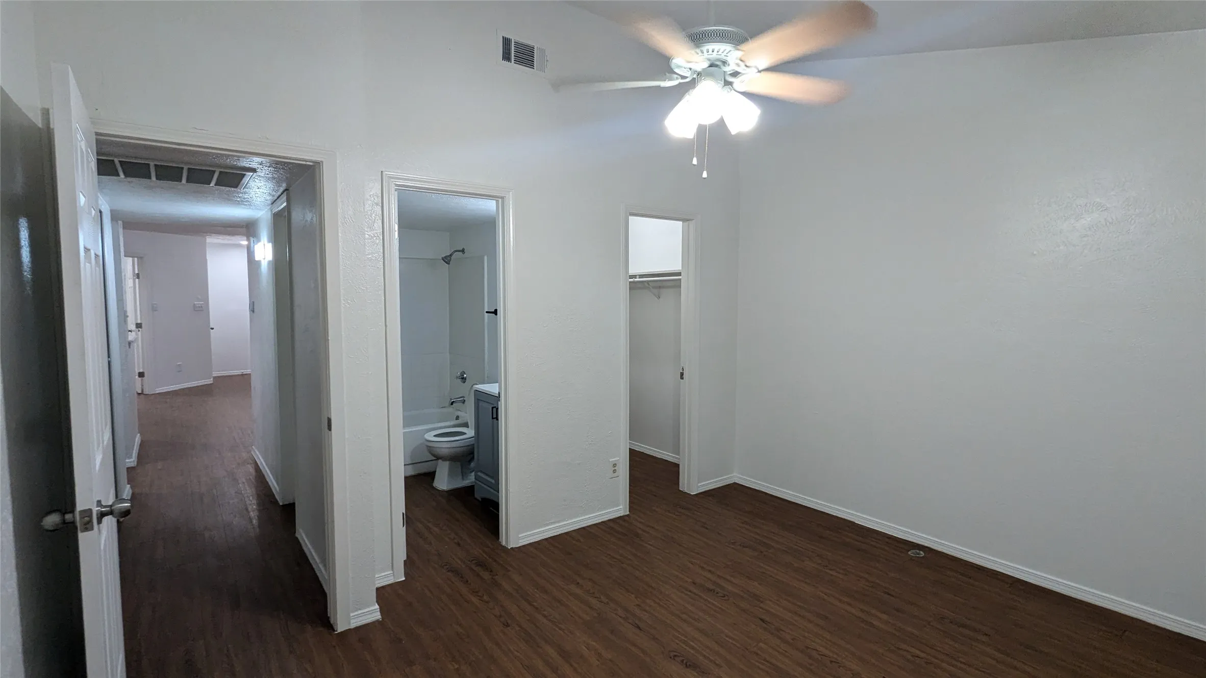 Wood-finish flooring, ceiling fan with integrated lighting, recessed closet, and a bathroom featuring a shower-tub combination and vanity
