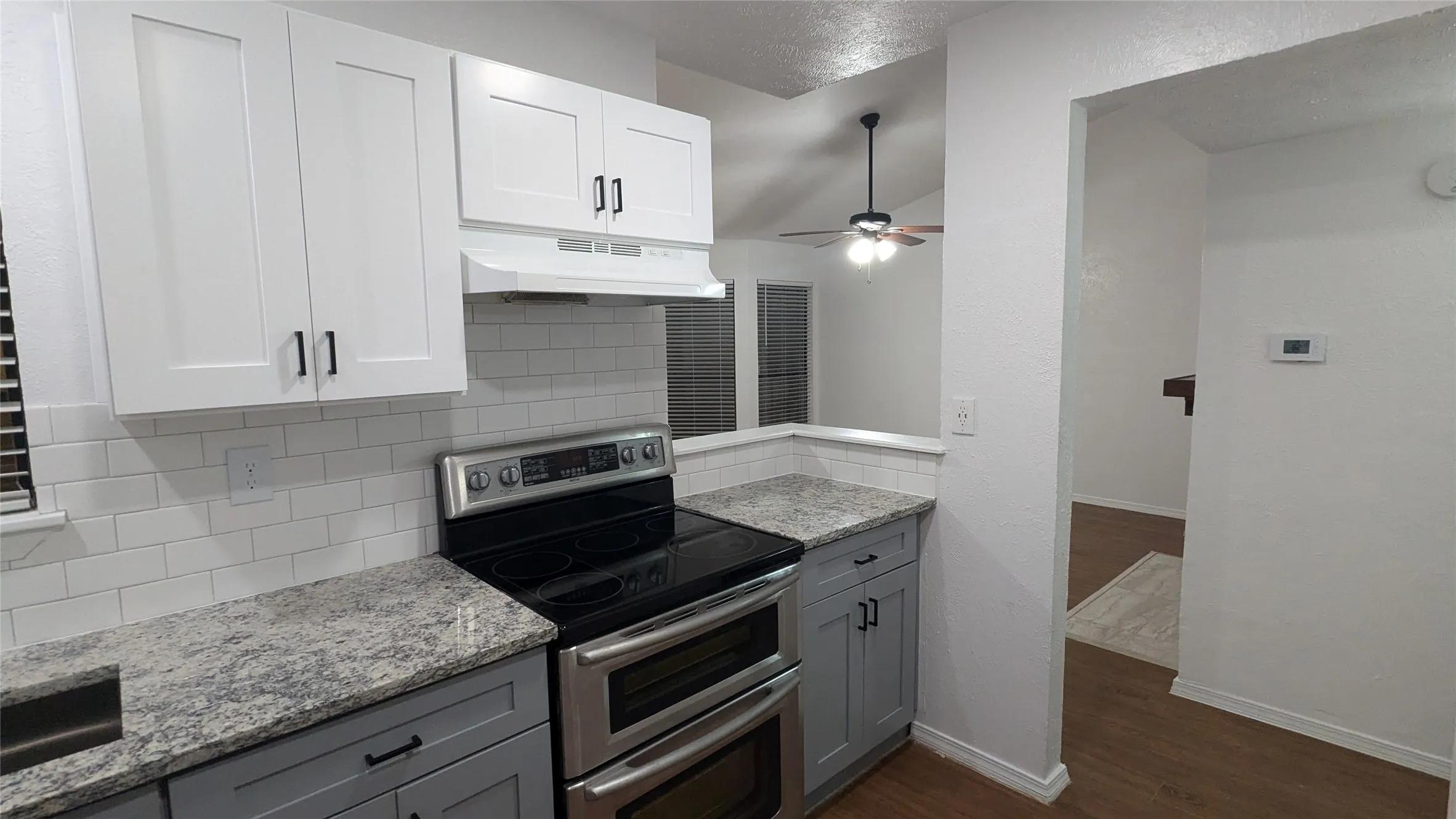 Modern kitchen featuring white upper cabinetry, gray lower cabinetry, and stainless steel appliances