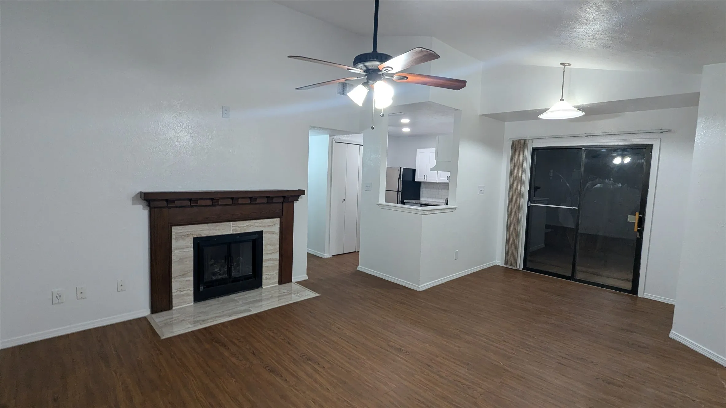 Living area featuring a fireplace with a wood mantle, wood-finish flooring, and a ceiling fan