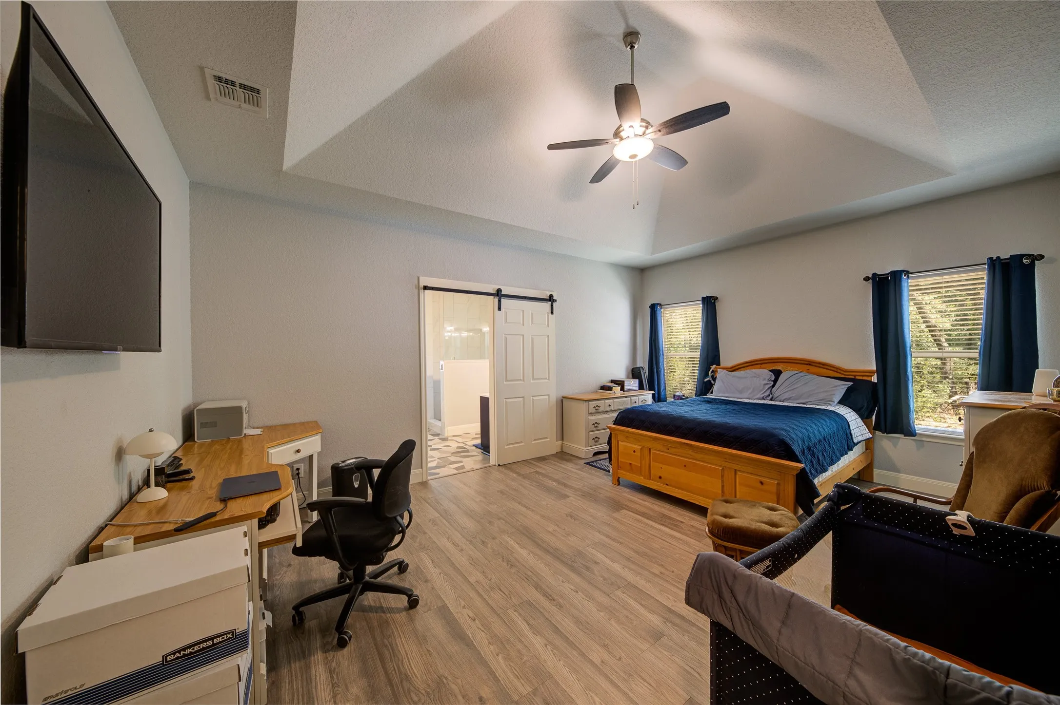 Vaulted ceiling with a ceiling fan, wood-finish flooring, and white walls