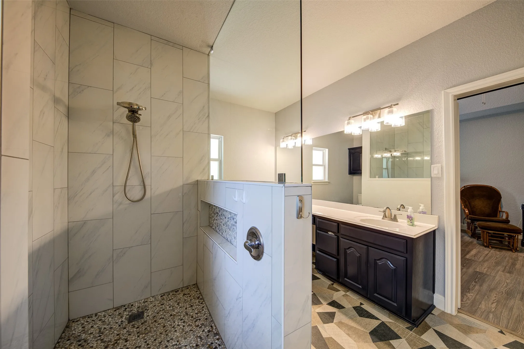 Walk-in shower with pebble tile flooring and tiled walls