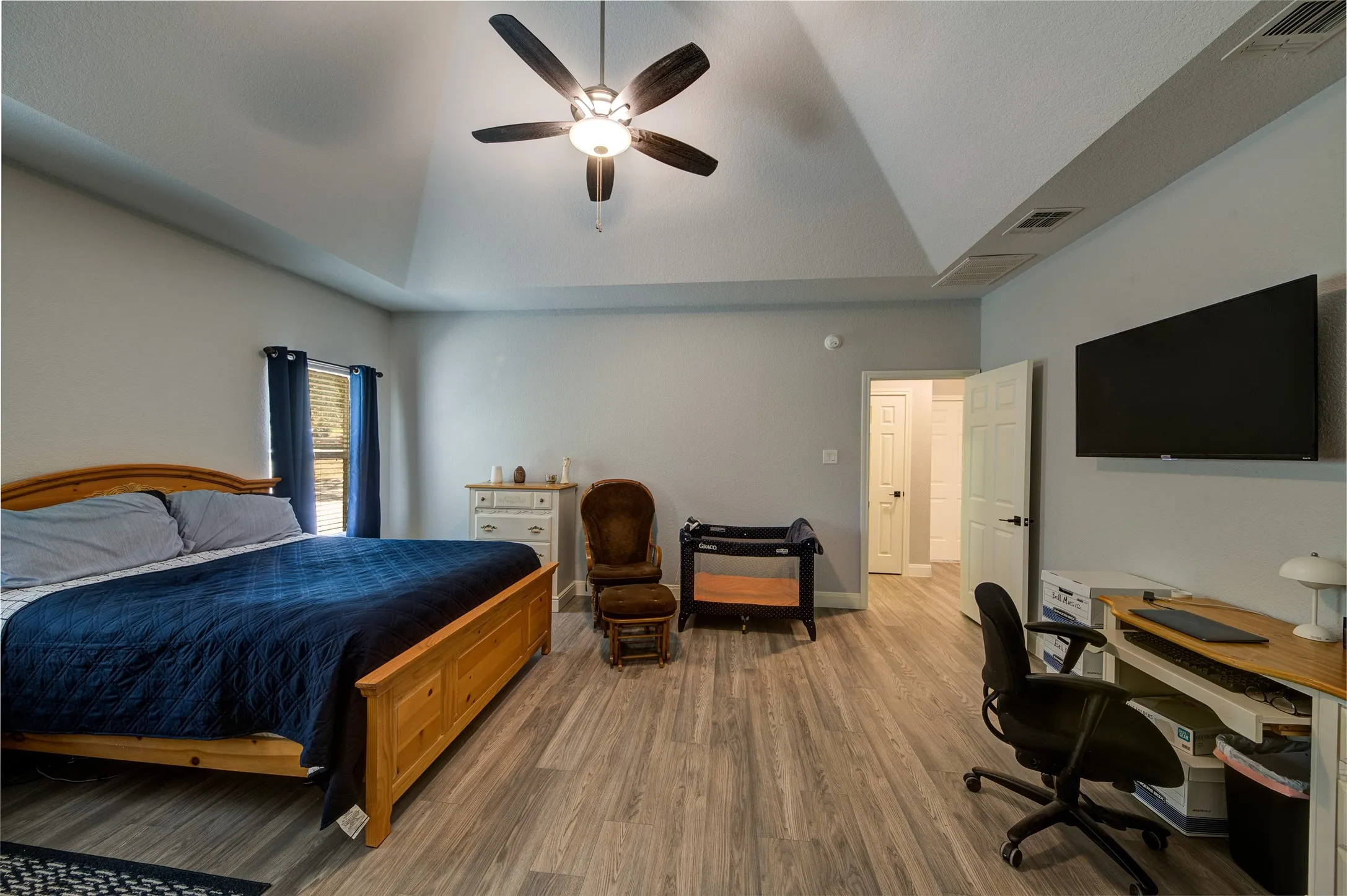 Veneer wood-finish flooring, vaulted ceiling, and ceiling fan with integrated lighting