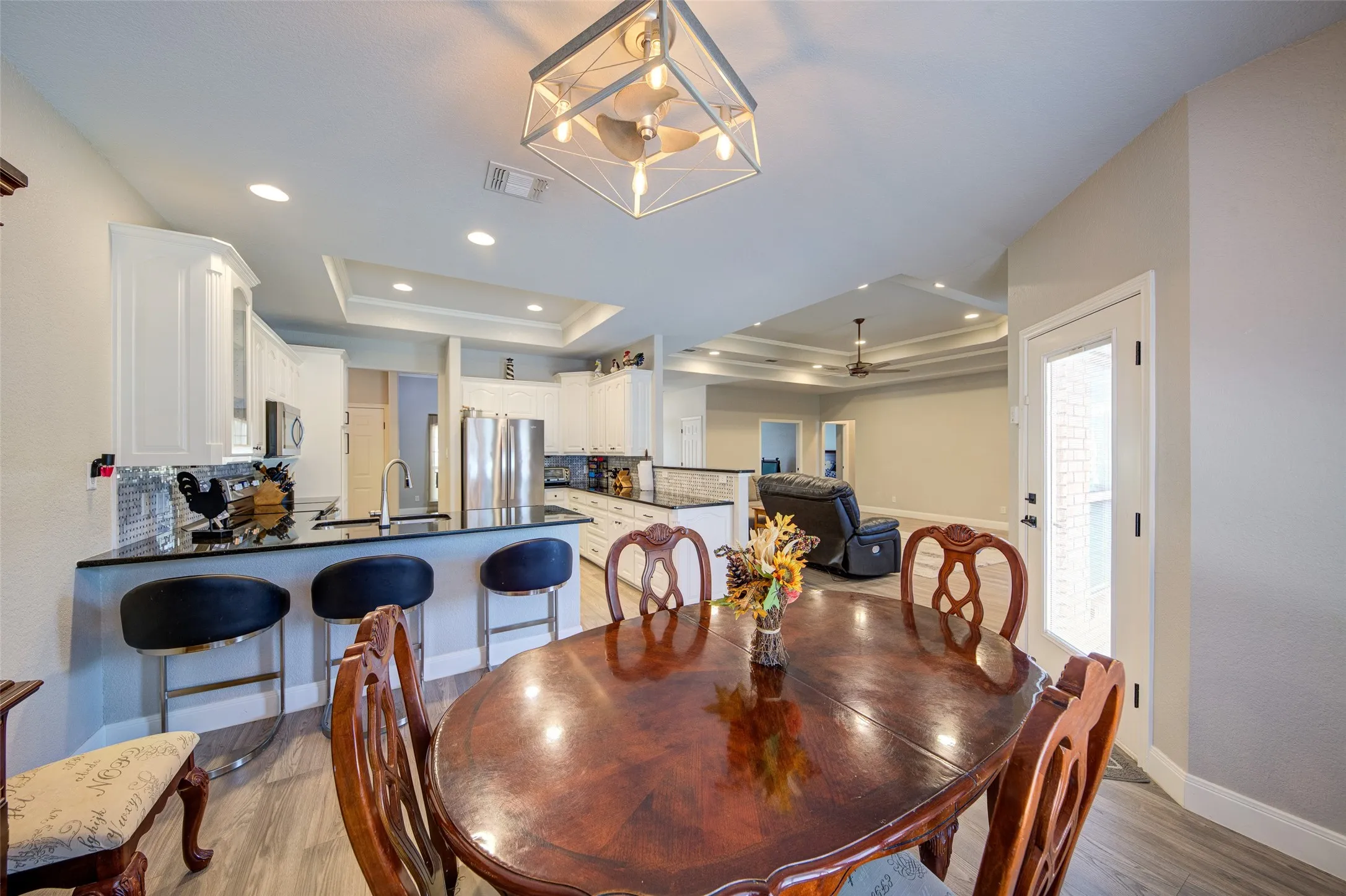 Kitchen featuring white cabinetry, breakfast bar, black countertops, and a subway tile backsplash