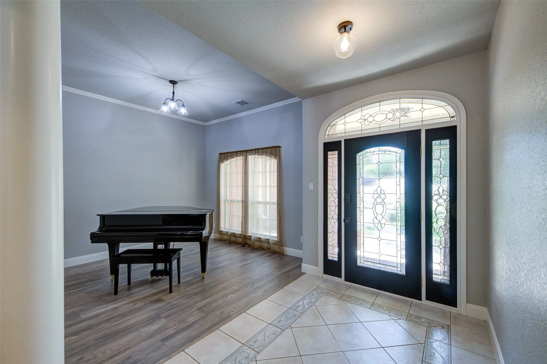 Entryway featuring an arched decorative glass front door with sidelights, tile flooring, and a flush mount light fixture