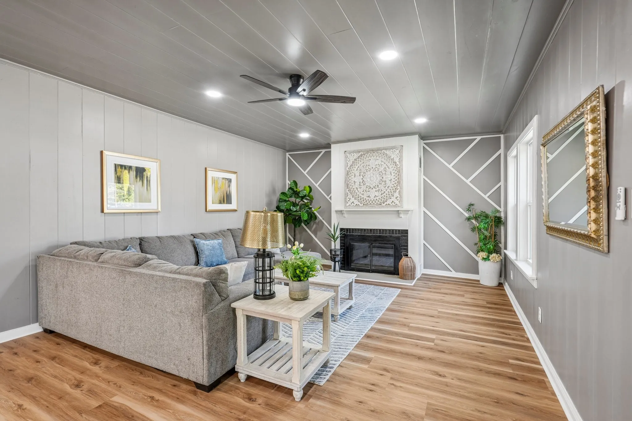 Recessed lighting, wood-finish flooring, ceiling fan, decorative fireplace surround, and geometric accent wall