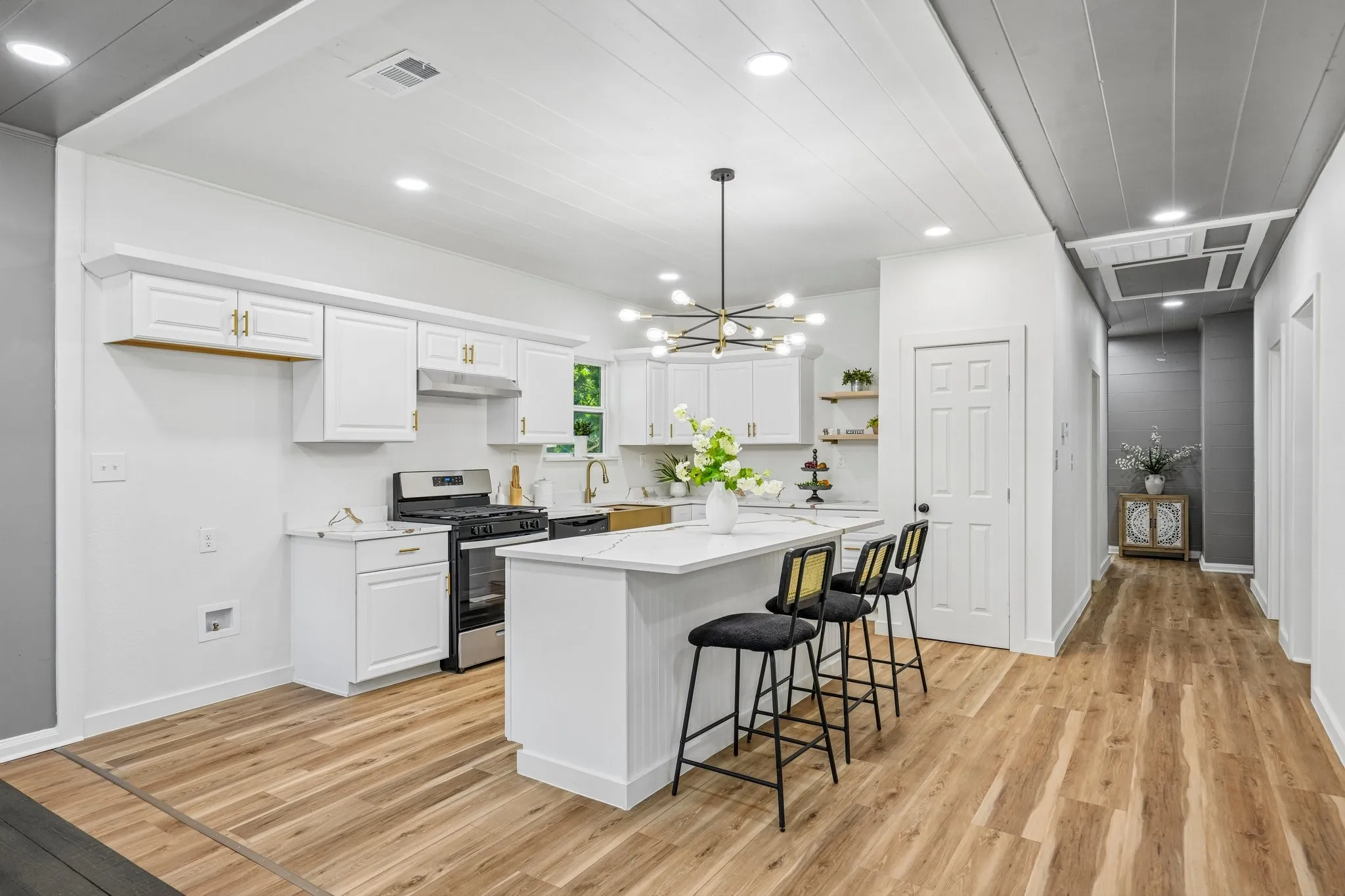Kitchen featuring white cabinetry, stainless steel appliances, a center island with countertop seating, wood-finish flooring, and recessed lighting