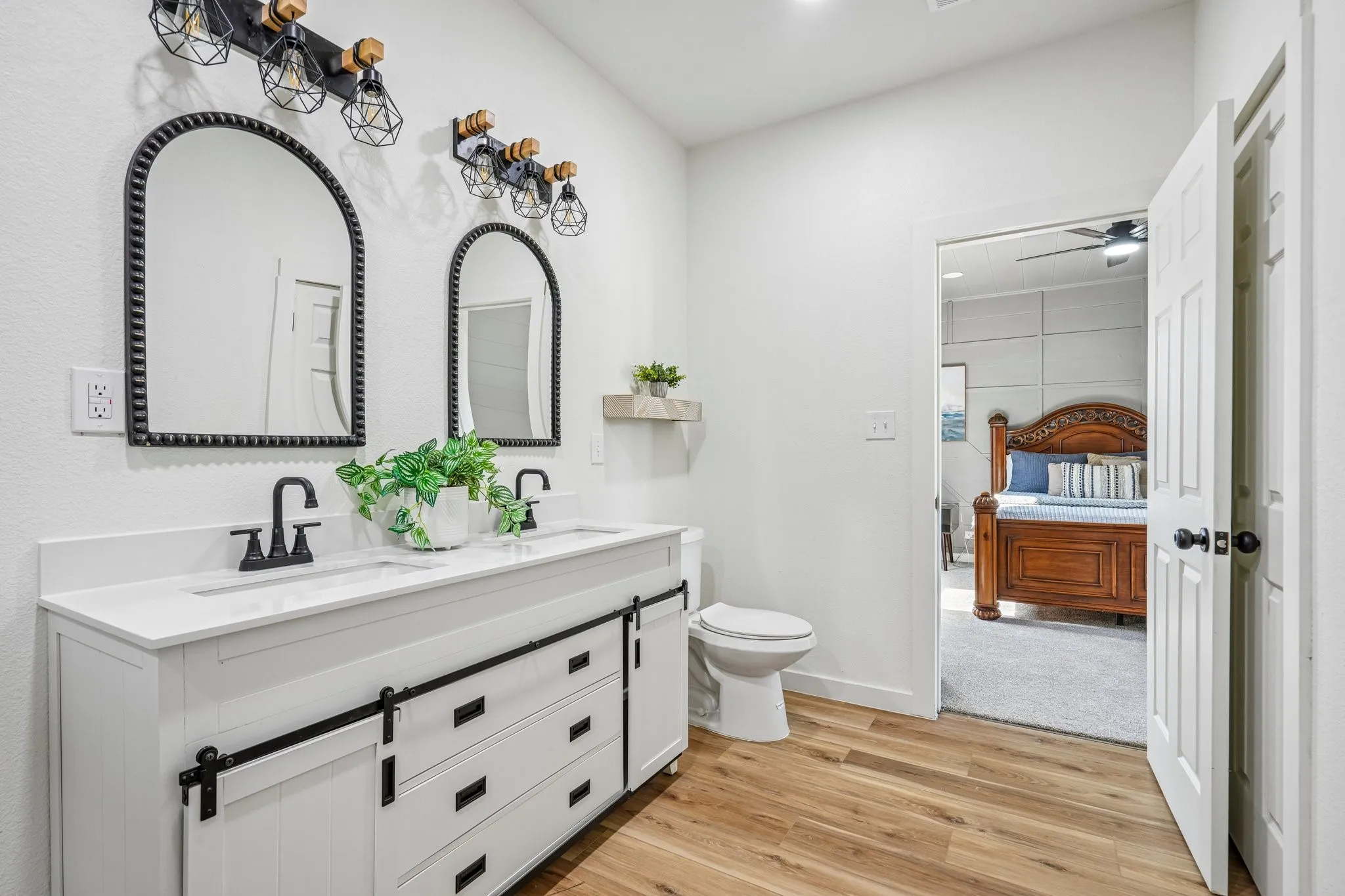 Double vanity with white countertop, matte black fixtures, and wood-finish flooring