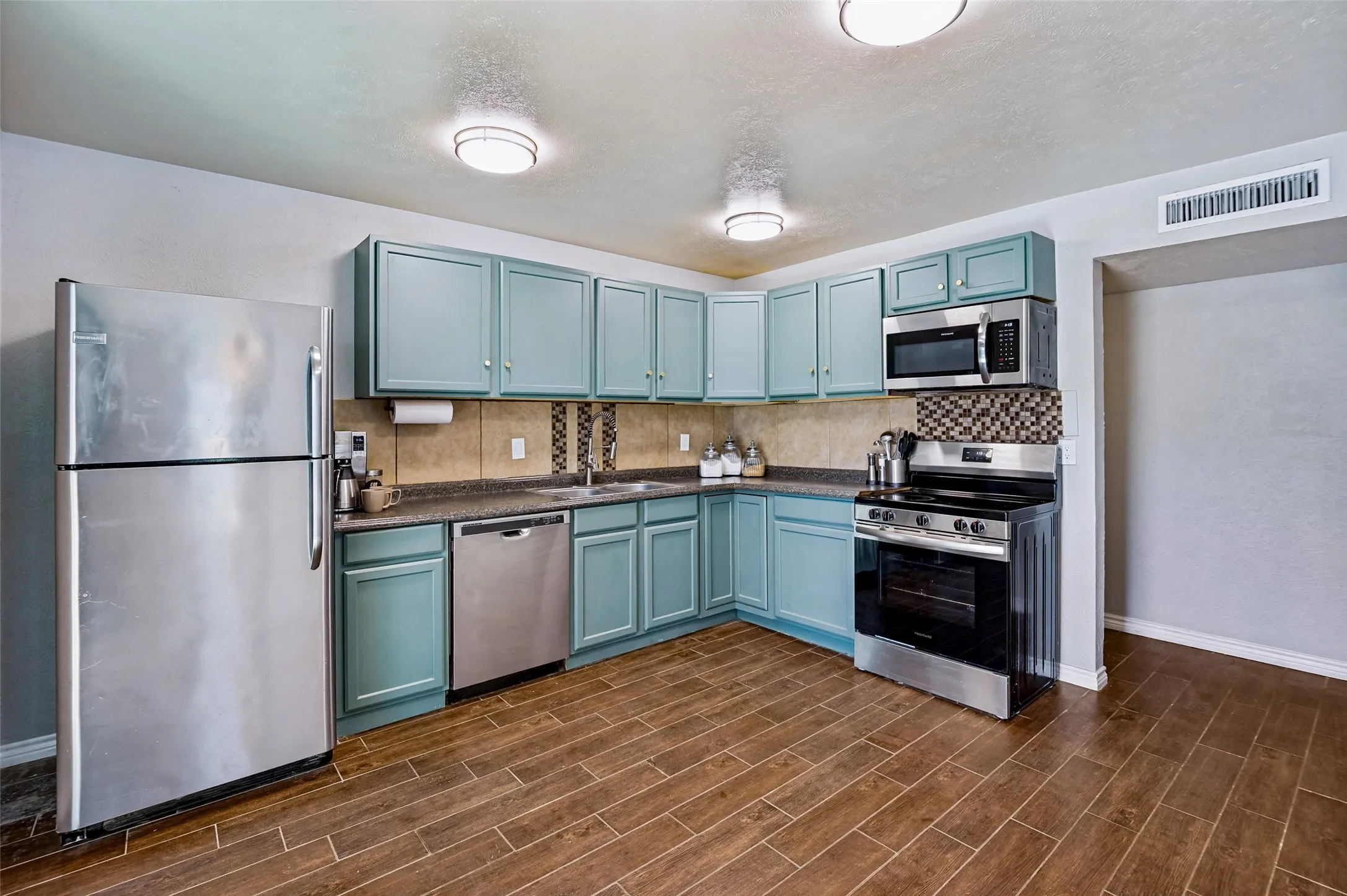 Stainless steel appliances and wood-look tile flooring enhances the kitchen