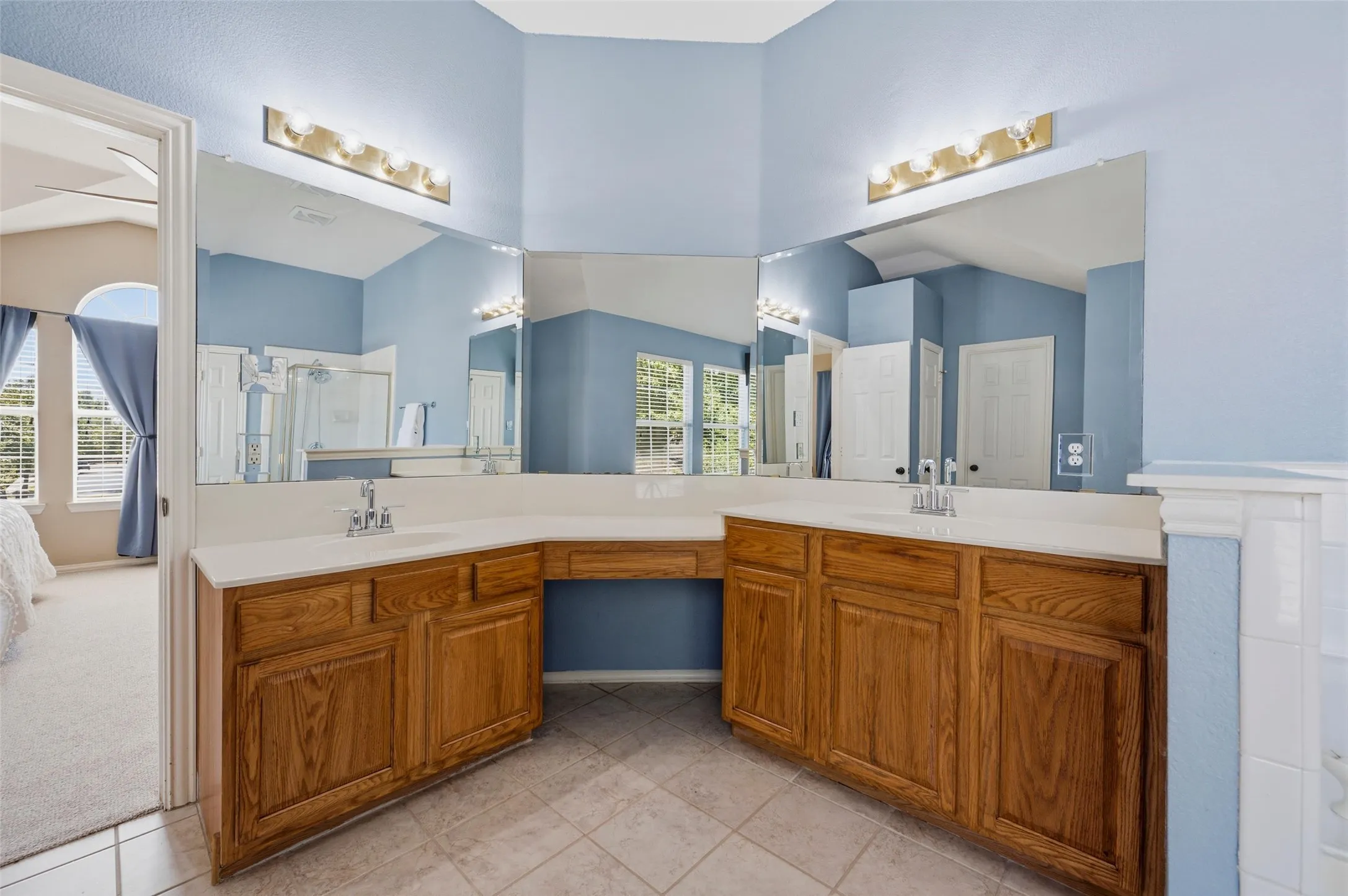 Dual vanity with wood-finish cabinetry, integrated sinks, and polished chrome fixtures