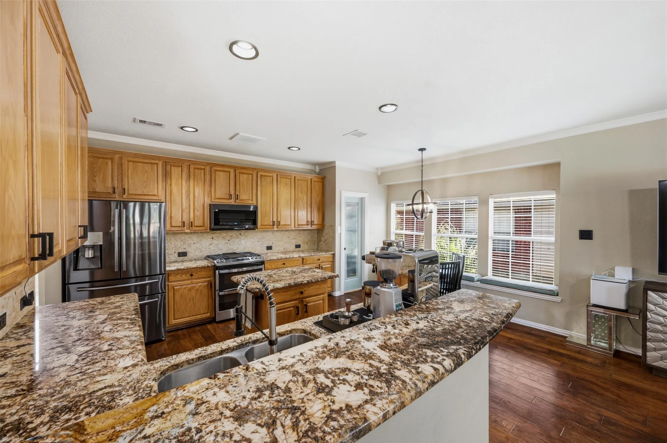 Kitchen featuring extensive wood cabinetry, stone countertops, stainless steel appliances, recessed lighting, and wood-finish flooring