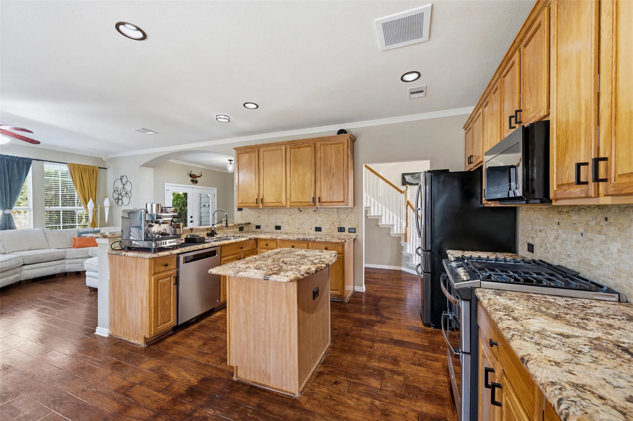 Kitchen featuring wood-finish flooring, light wood cabinetry, stone countertops, stainless steel appliances, and recessed lighting