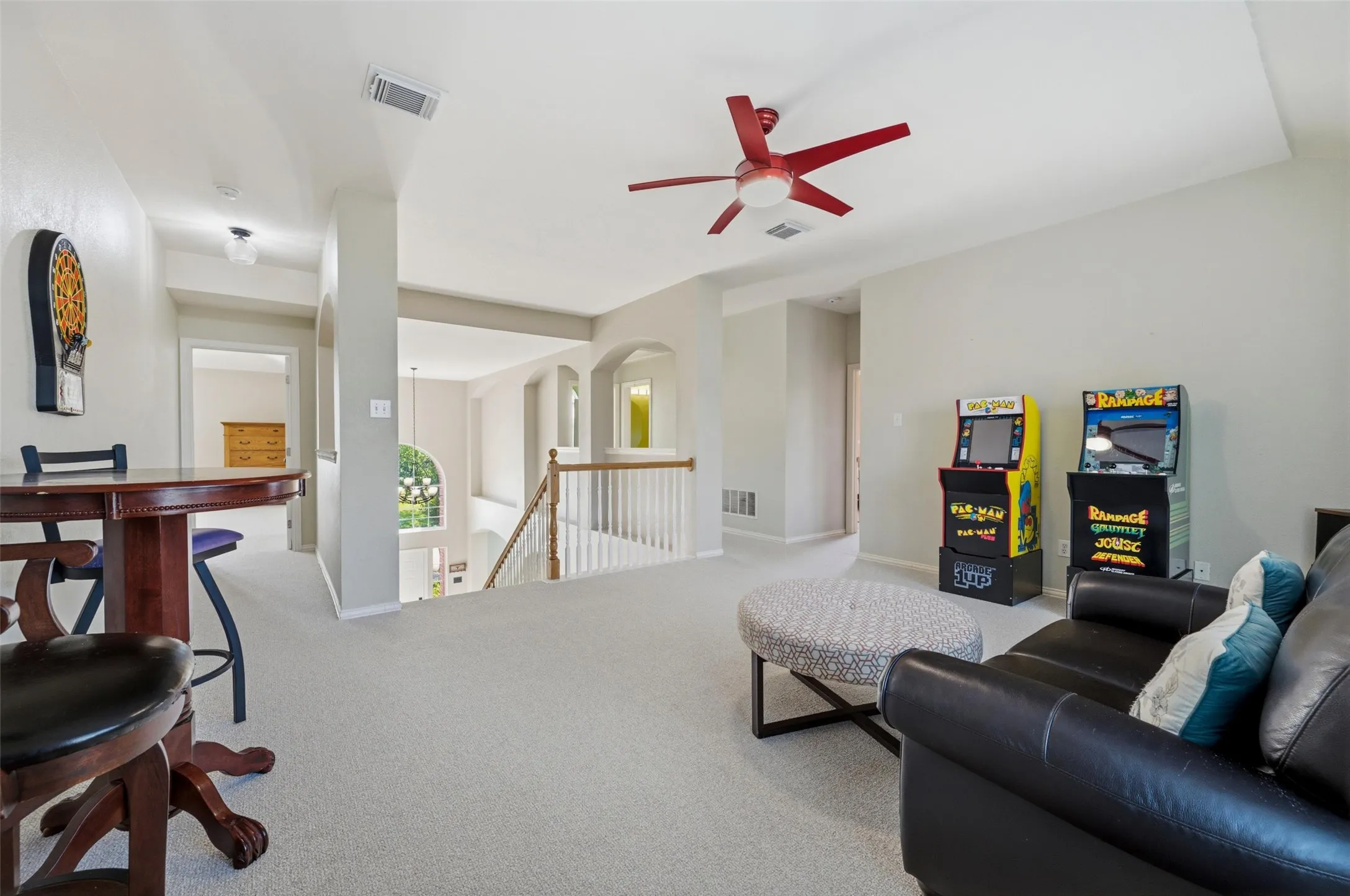 Loft space with carpeting, a ceiling fan, and architectural archways
