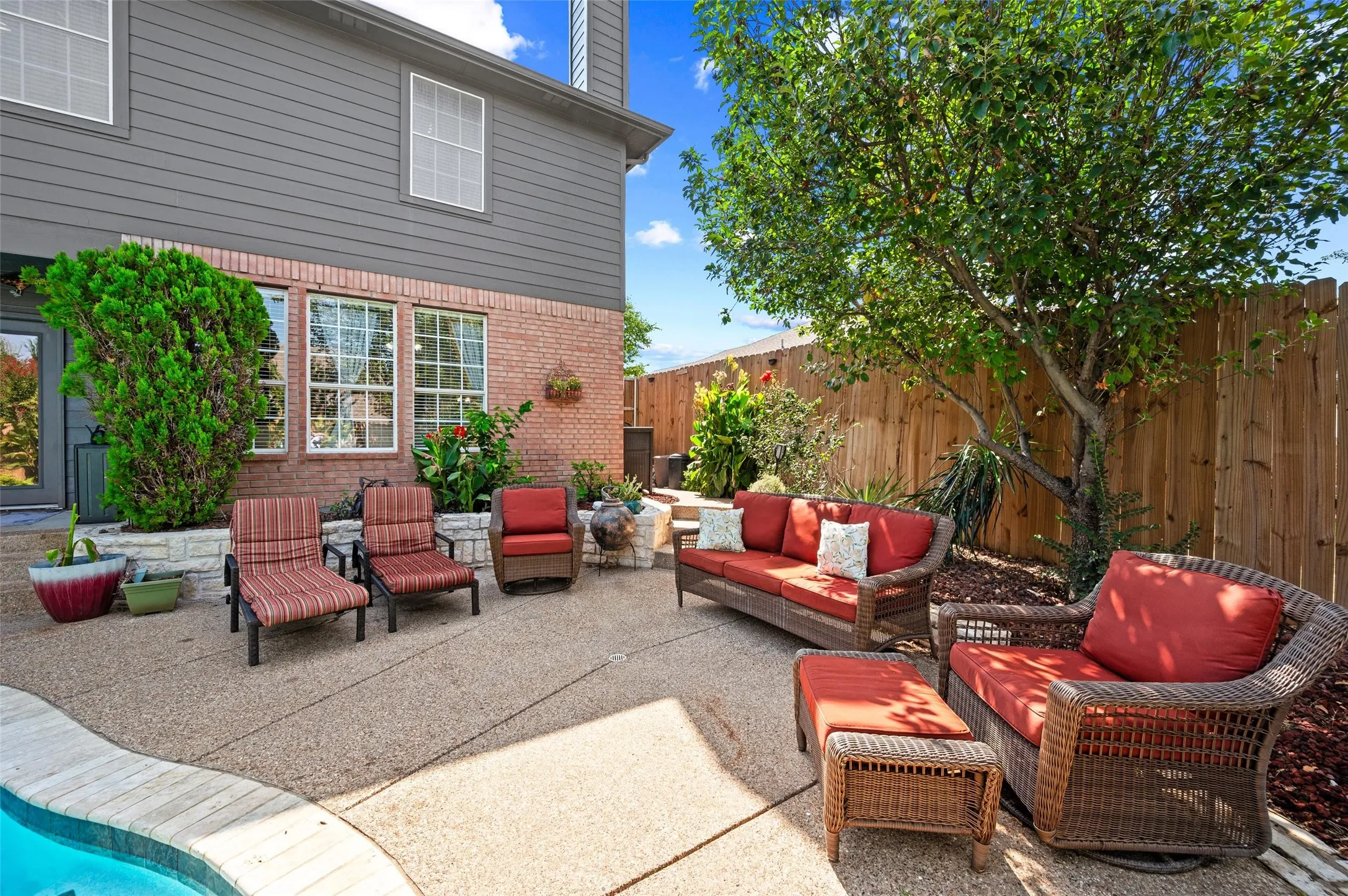 Exterior featuring a wood privacy fence, brick and siding facade, and a ground-level patio