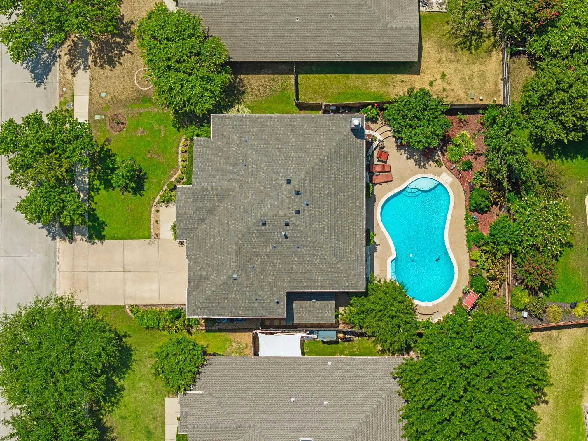 Residence featuring a private swimming pool, mature trees, concrete driveways, and expansive green spaces