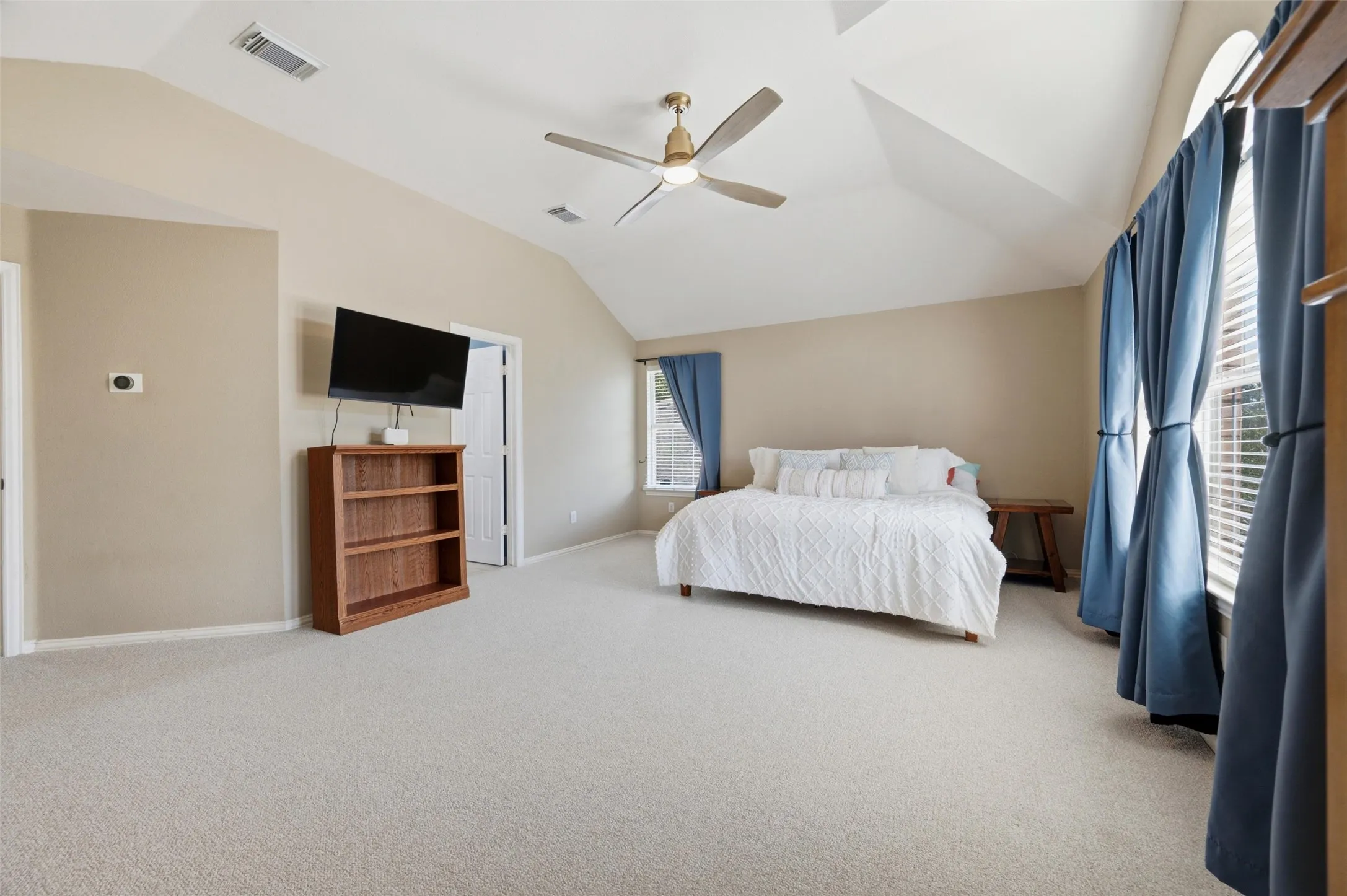 Vaulted ceiling with an attached ceiling fan, arched window, and neutral wall tones